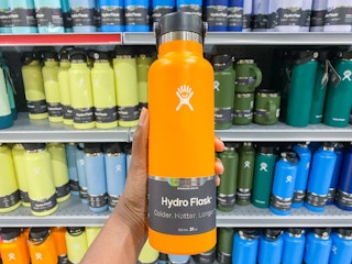 a hydroflask being held in front of a display of other hydrflasks