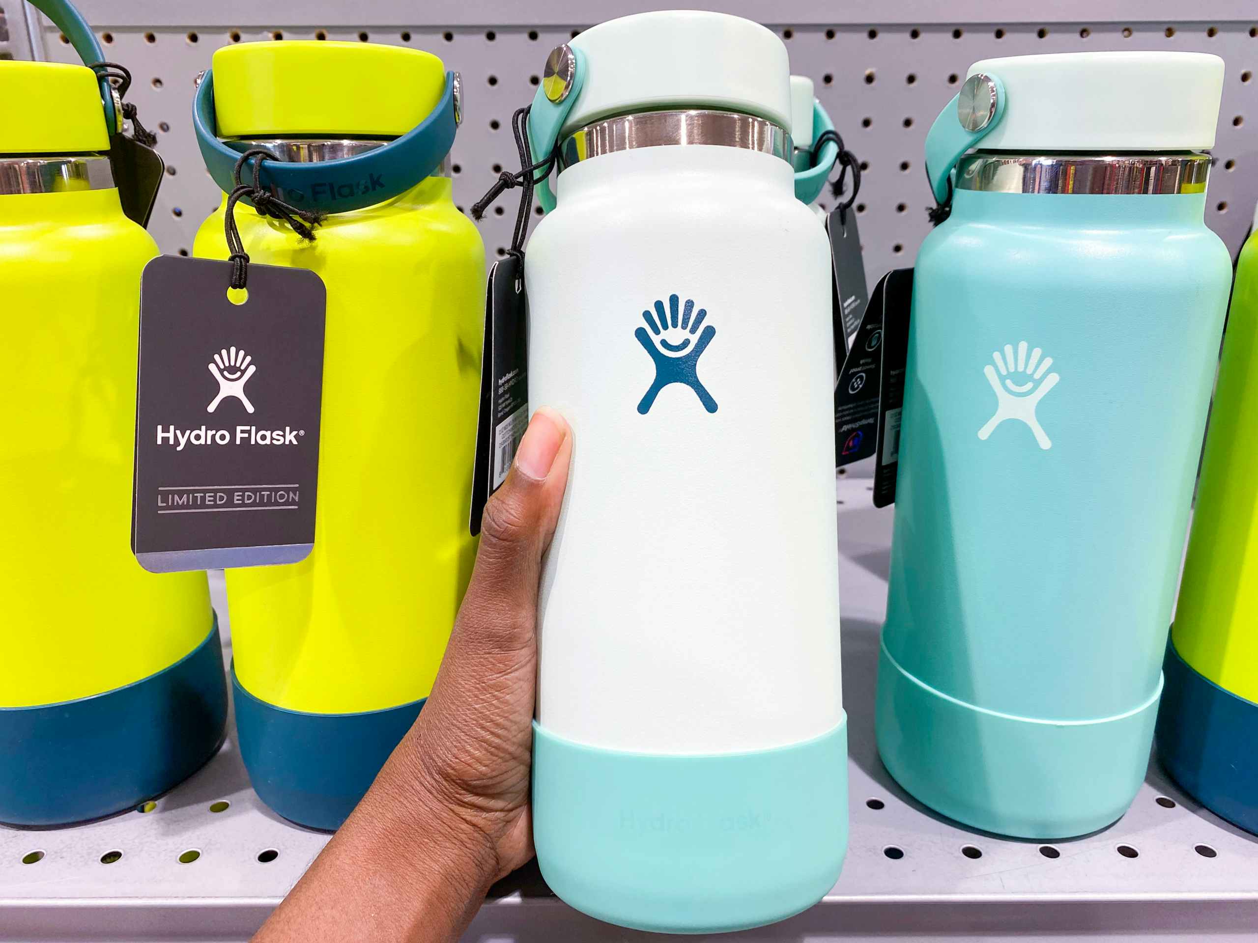 a hydroflask being held in front of a display of other hydrflasks