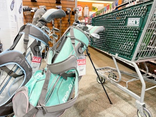 Topflight gold clubs in golf bags next to a Dicks Sporting Goods shopping cart