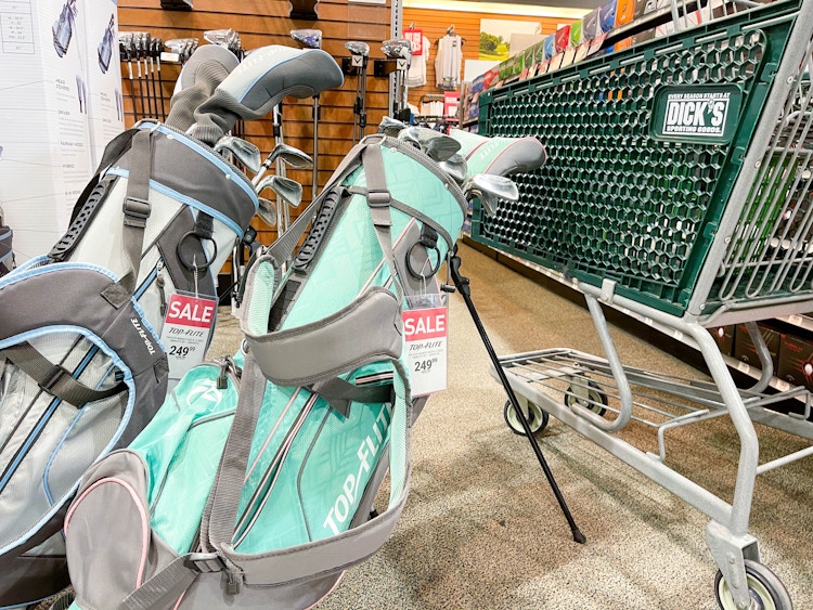 Topflight gold clubs in golf bags next to a Dicks Sporting Goods shopping cart