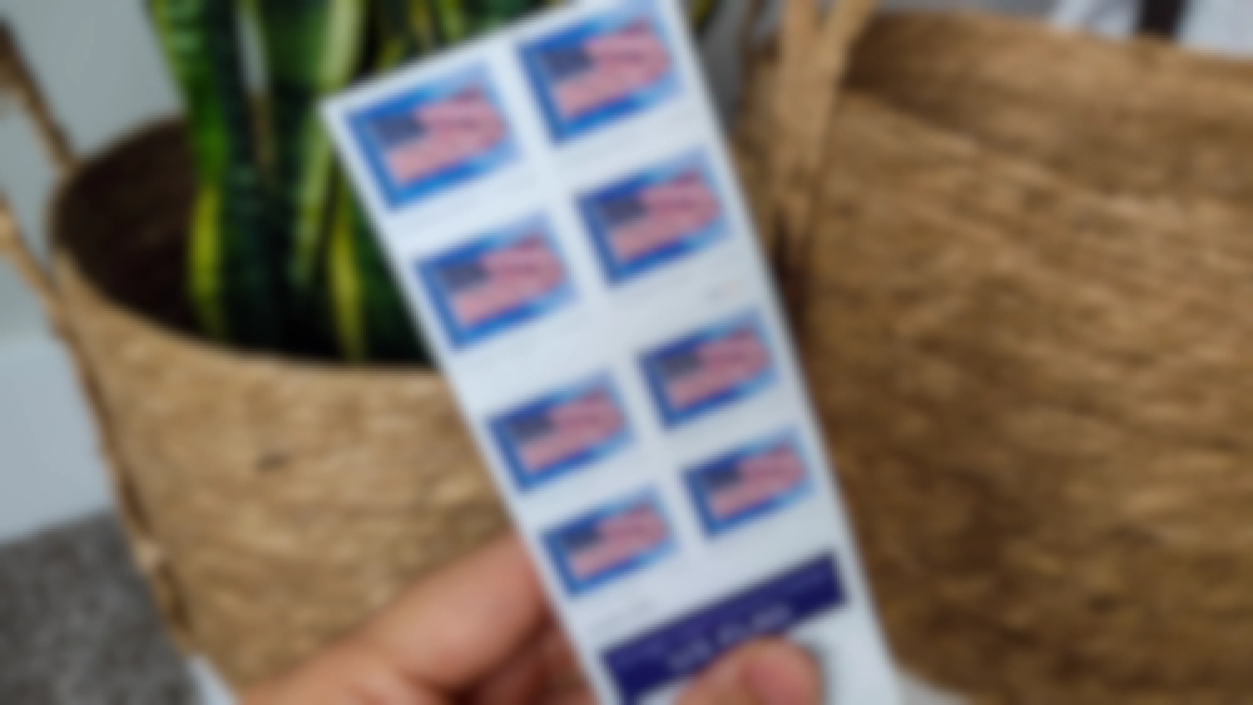 A person's hand holding some American flag Forever postage stamps.