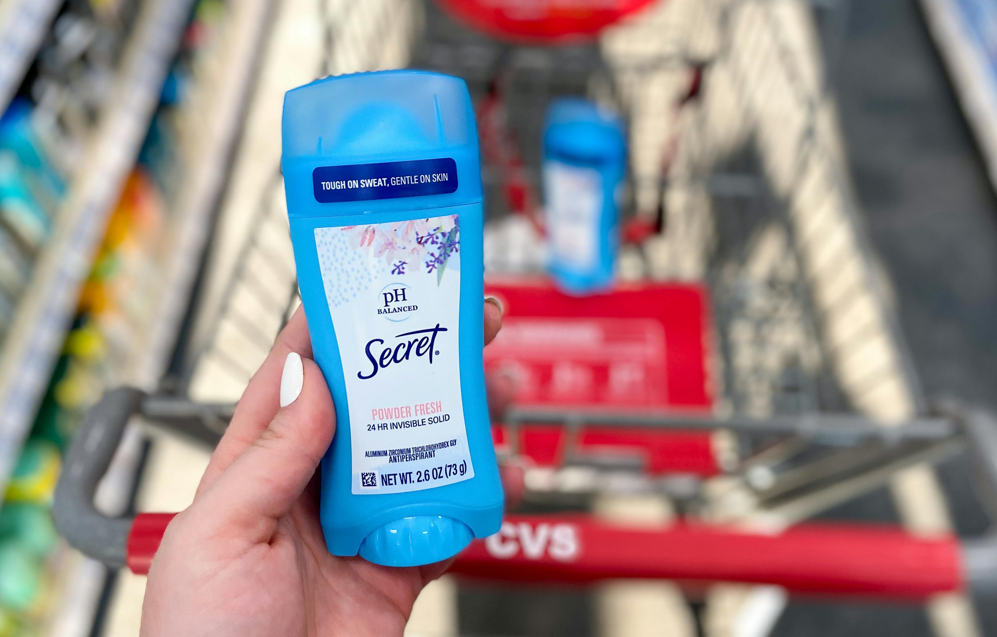 someone holding secret deodorant next to cvs cart