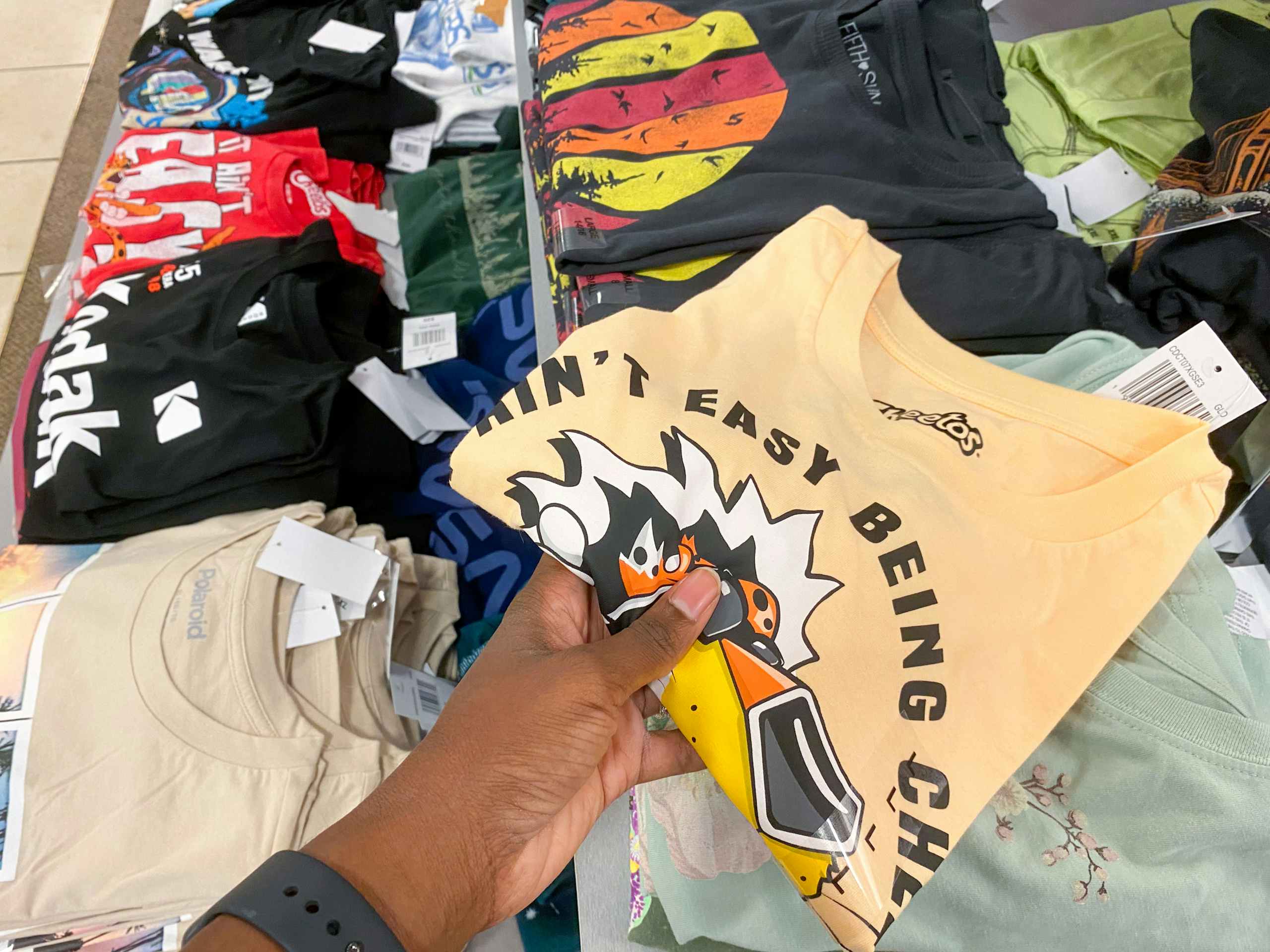 someone picking up a shirt on a display of other t-shirts