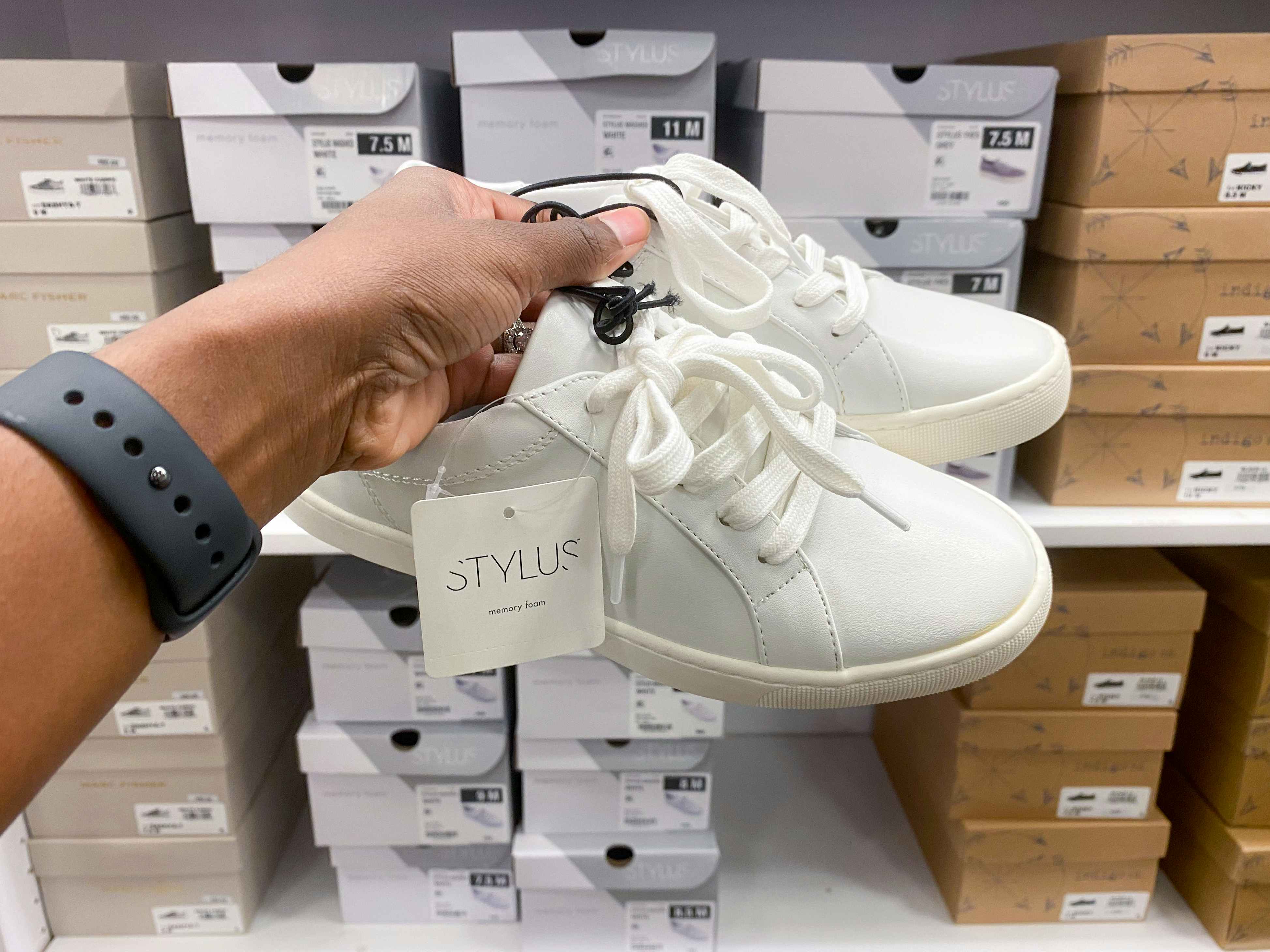 someone holding a pair of shoes in front of a shelf of shoe boxes