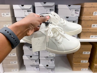 someone holding a pair of shoes in front of a shelf of shoe boxes