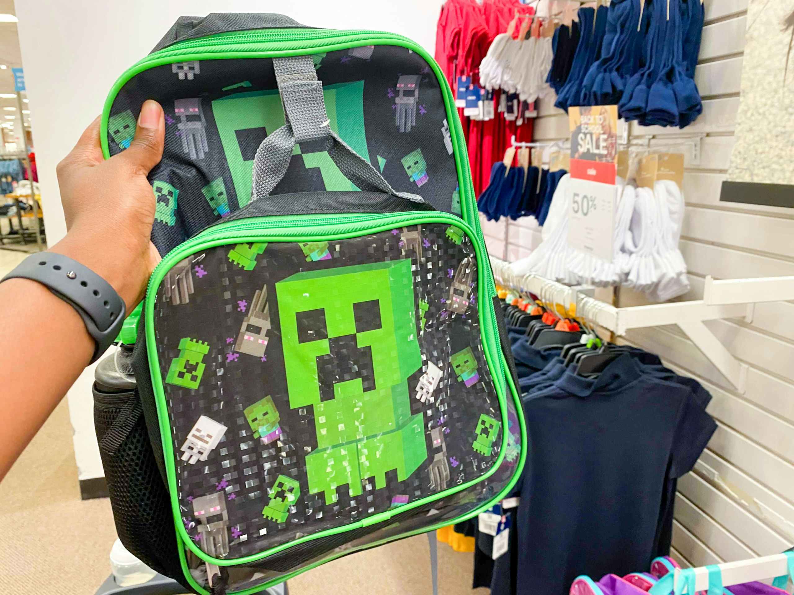 someone grabbing a backpack in the kids clothing section at jcpenney