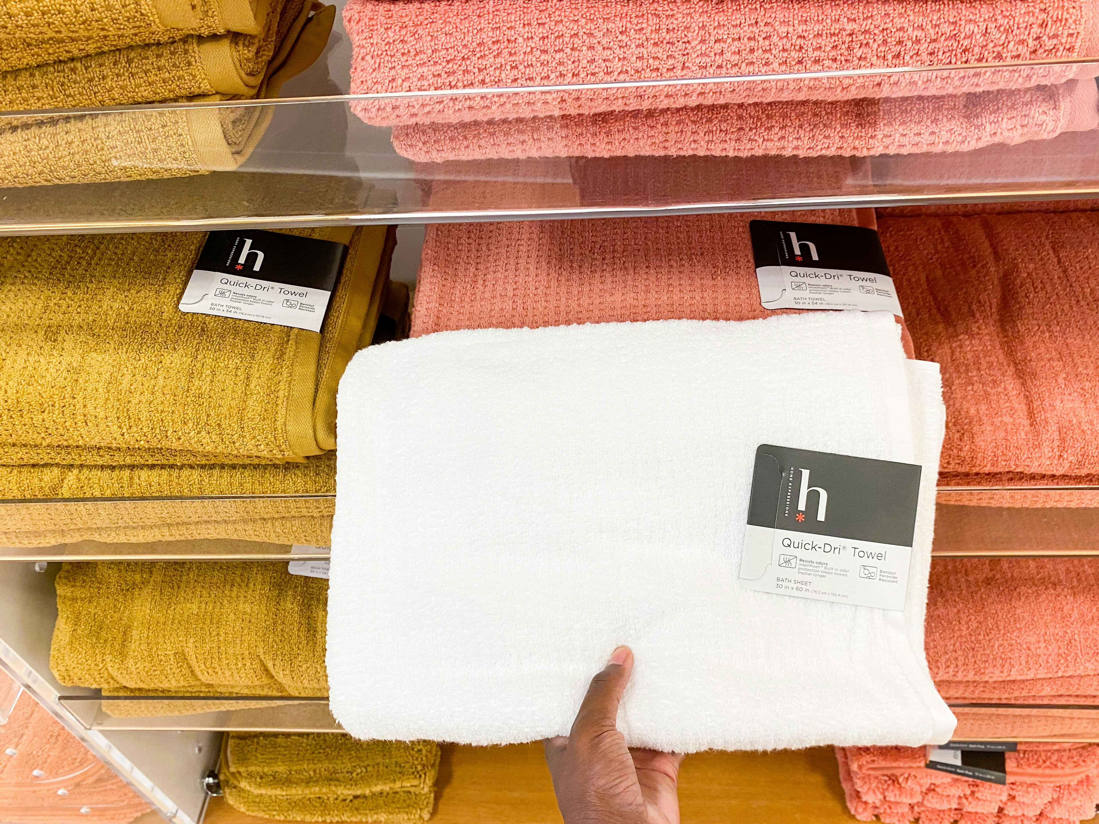 a person holding a bath towel in the towel section in jcpenney