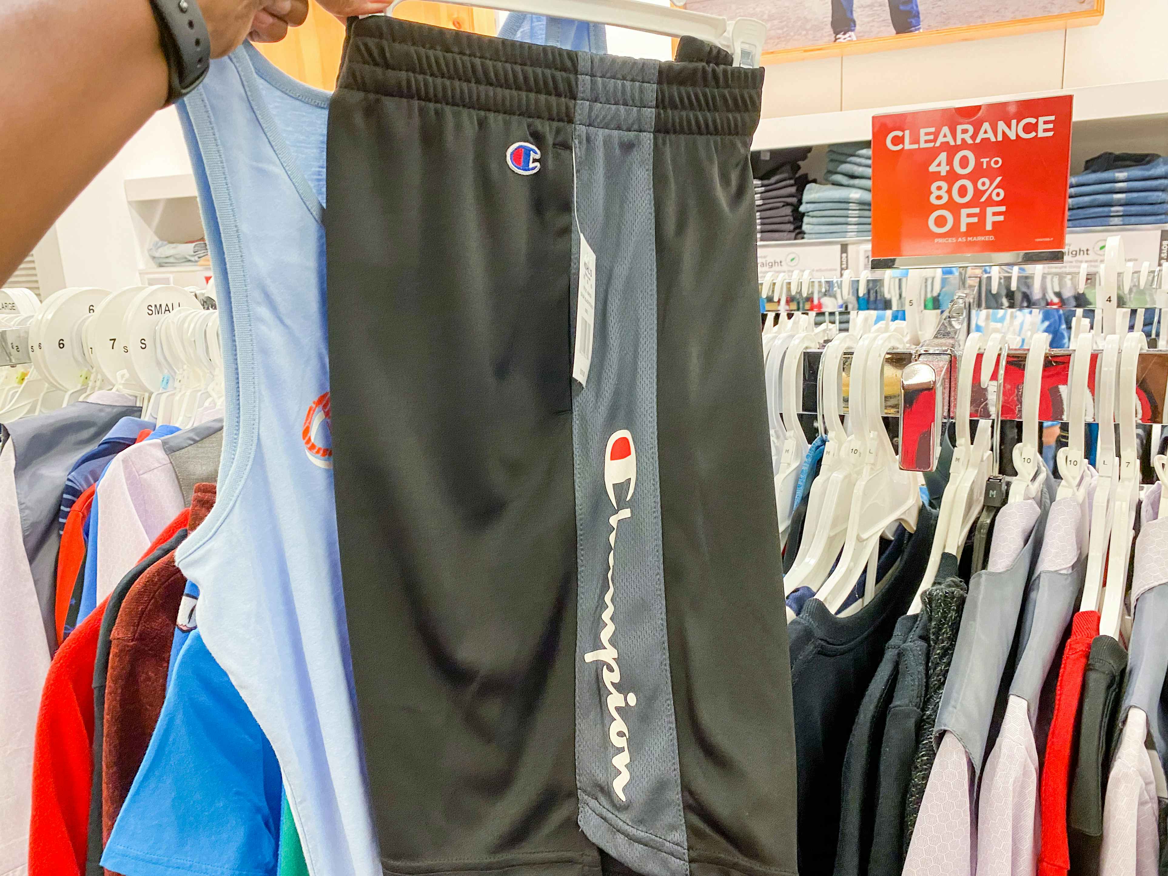 someone holding a shirt and a pair of shorts in front of the clearance section
