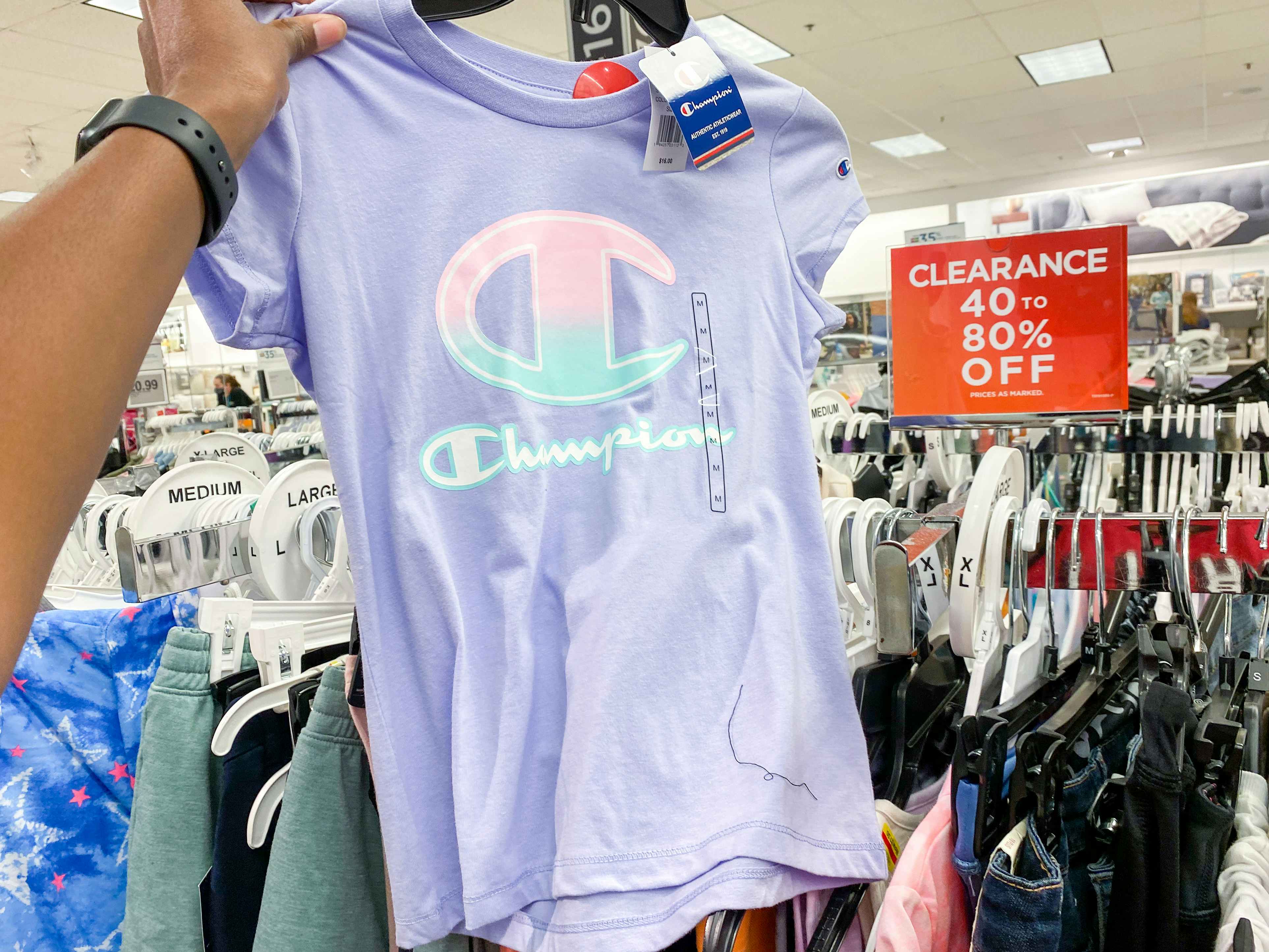 someone holding a shirt in front of a clearance section