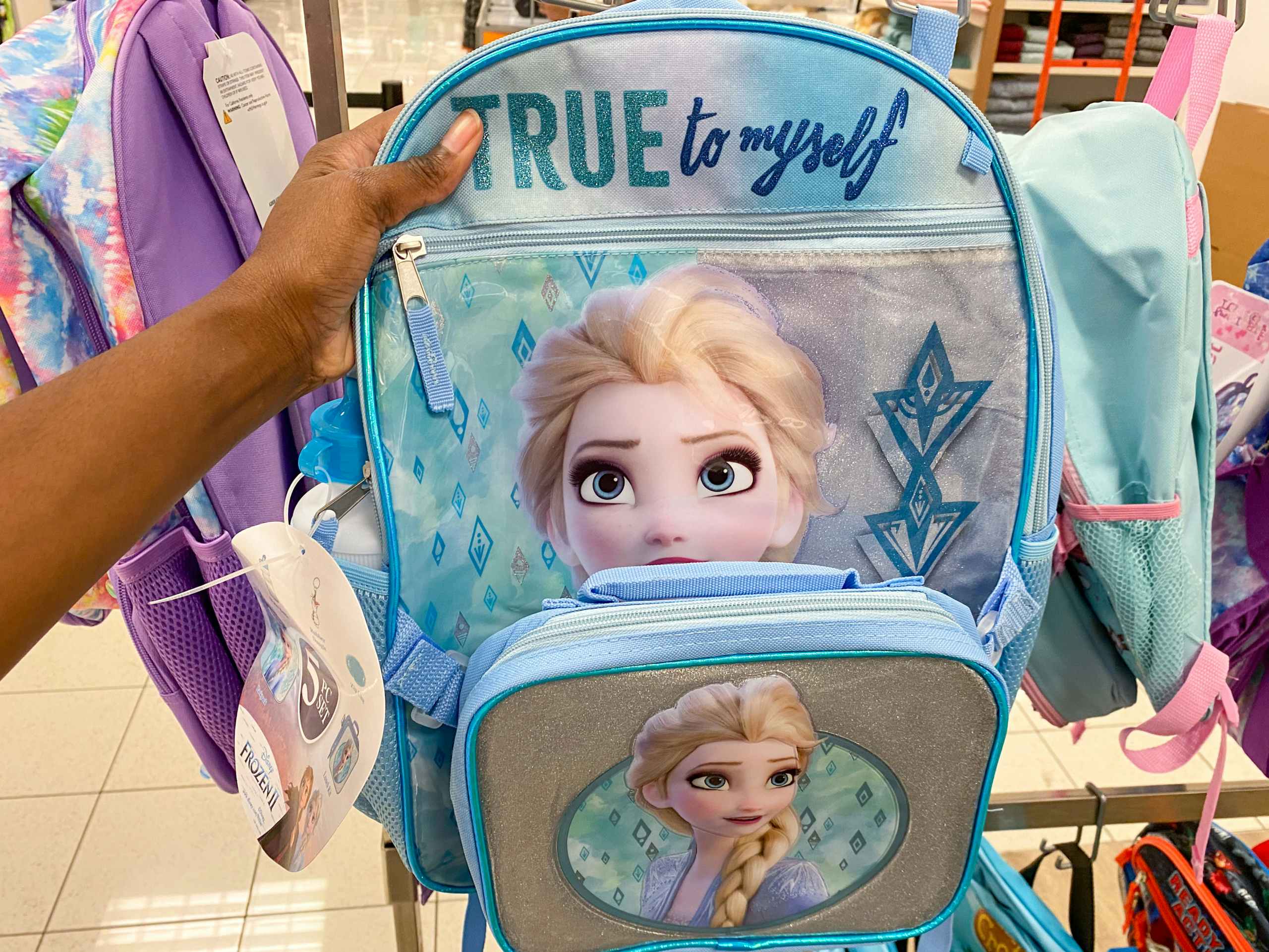 a frozen backpack being held on a rack full of backpacks in kohls
