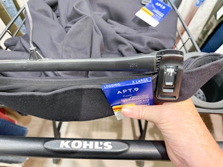 A person putting clearance black leggings into a Kohl's shopping cart.