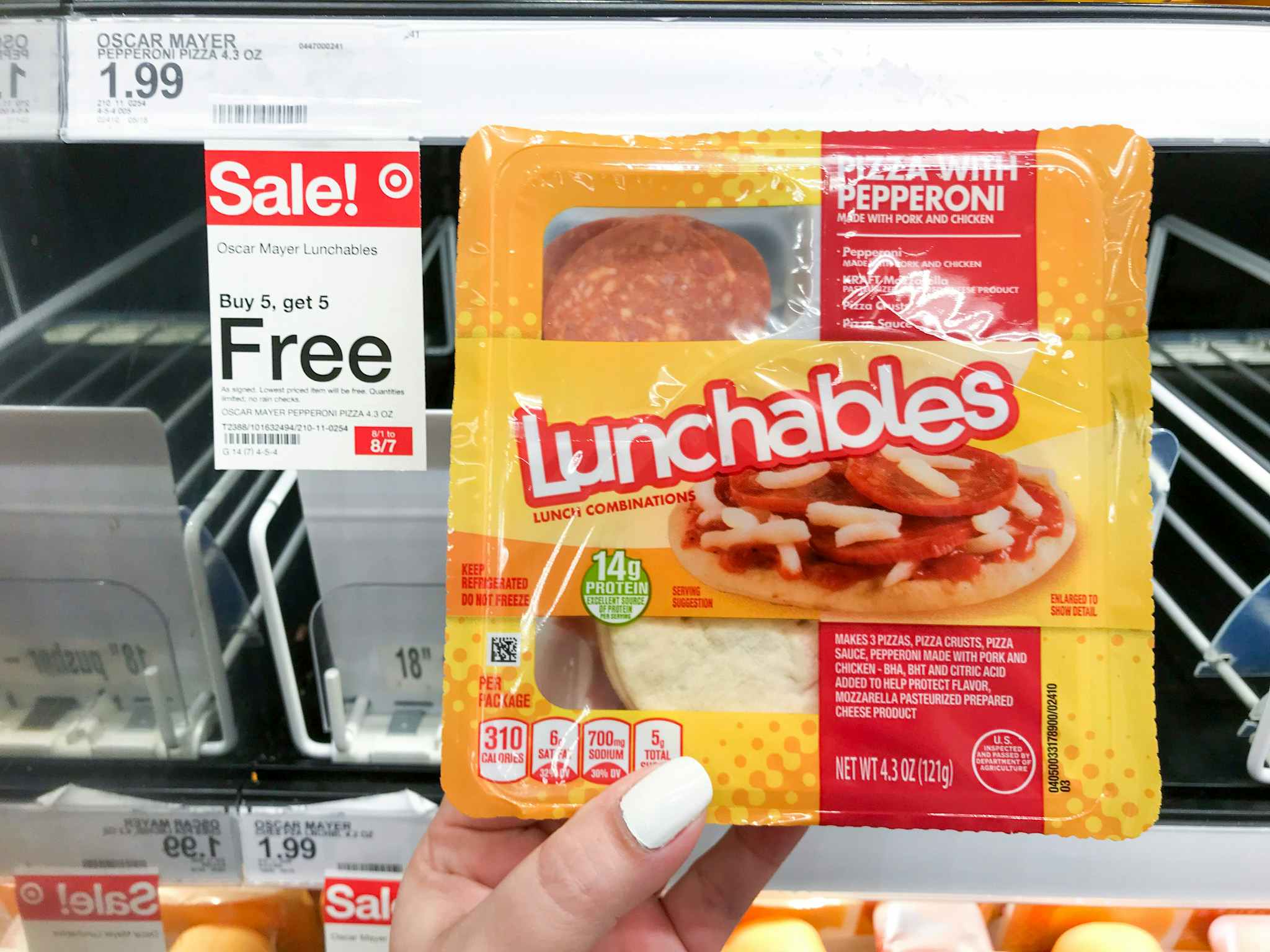 hand holding lunchables in front of sale tag at target