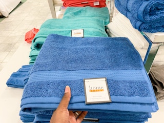 a bath towel being taken off a shelf filled with other towels