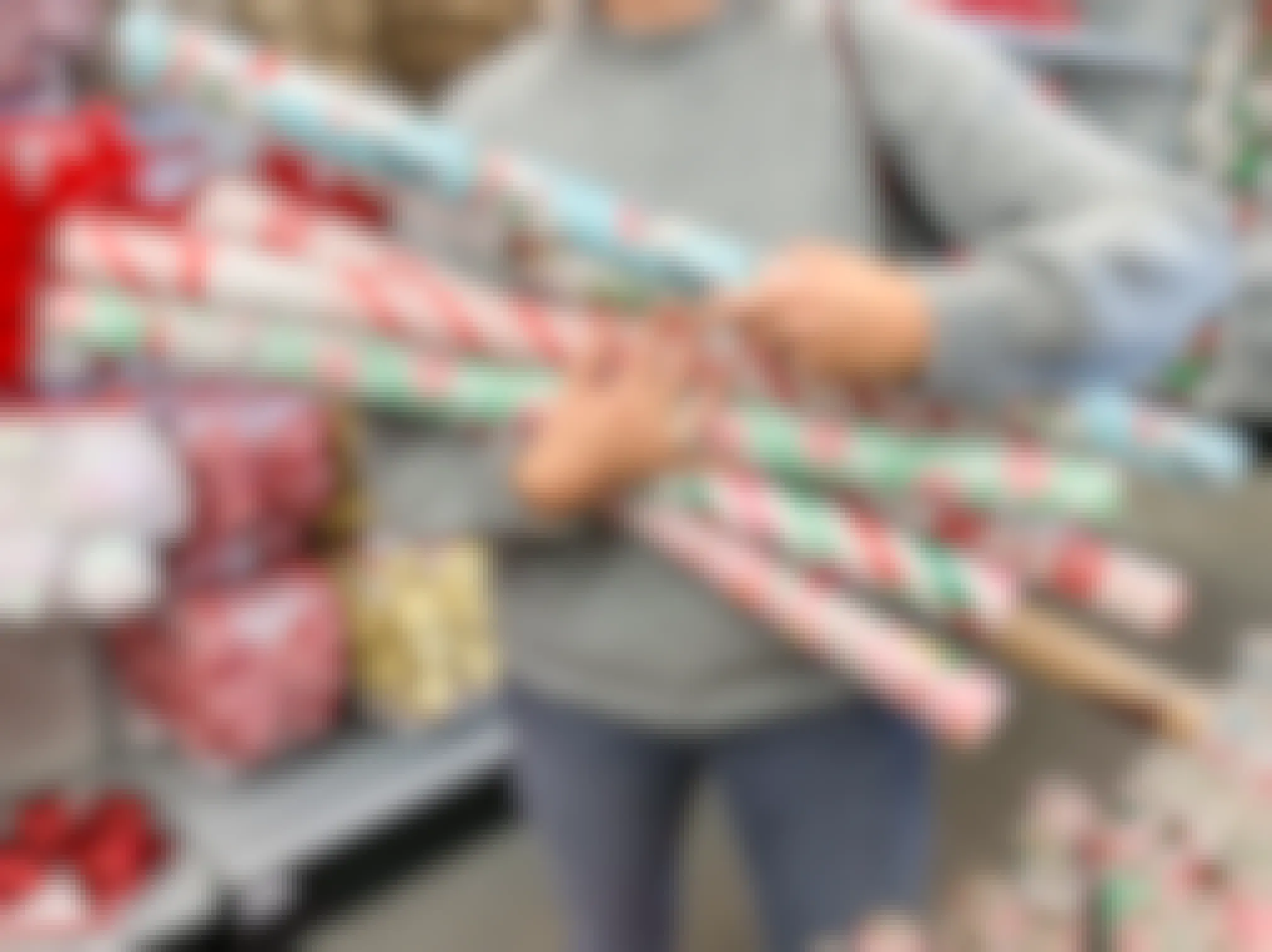 A woman holding an arm full of Christmas gift wrap