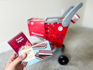 hand holding target mini food items next to mini toy shopping cart