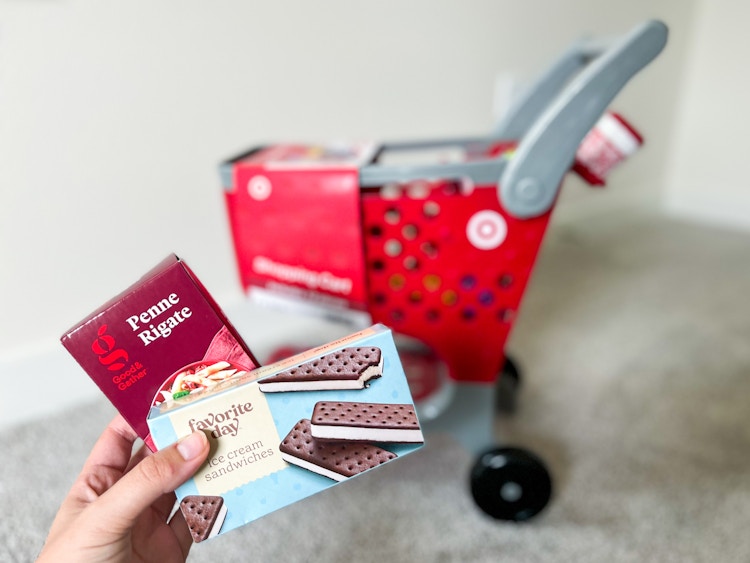 hand holding target mini food items next to mini toy shopping cart
