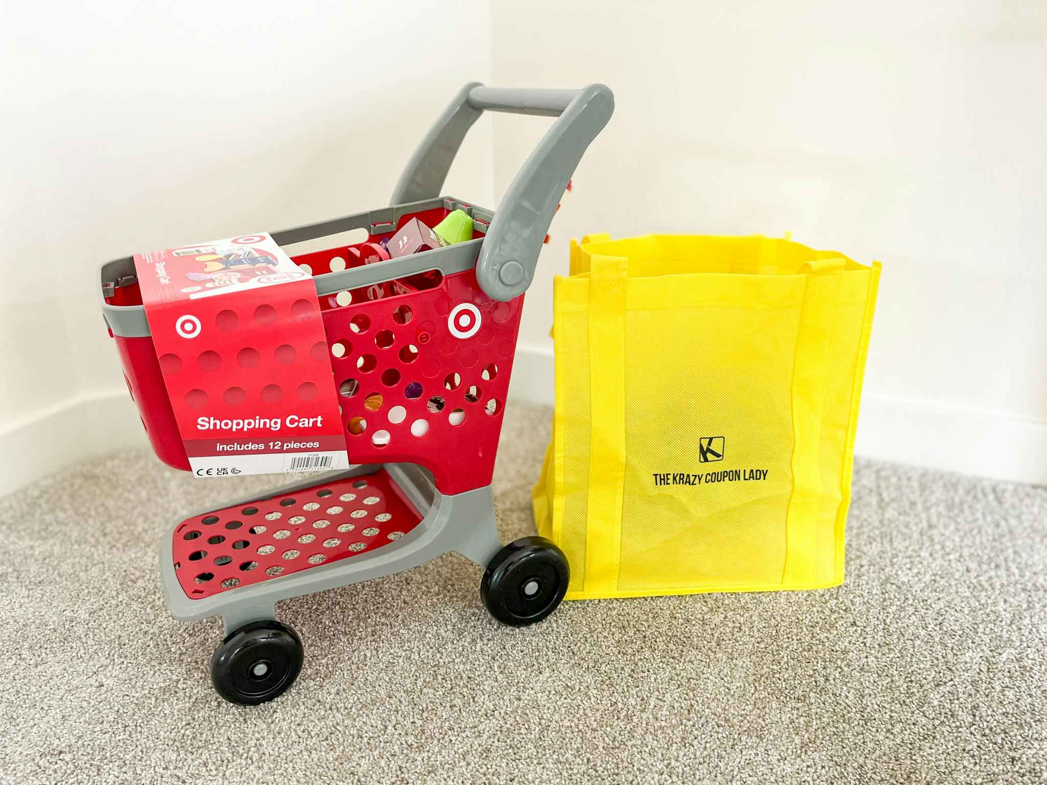 A Target toy shopping cart next to a KCL bag