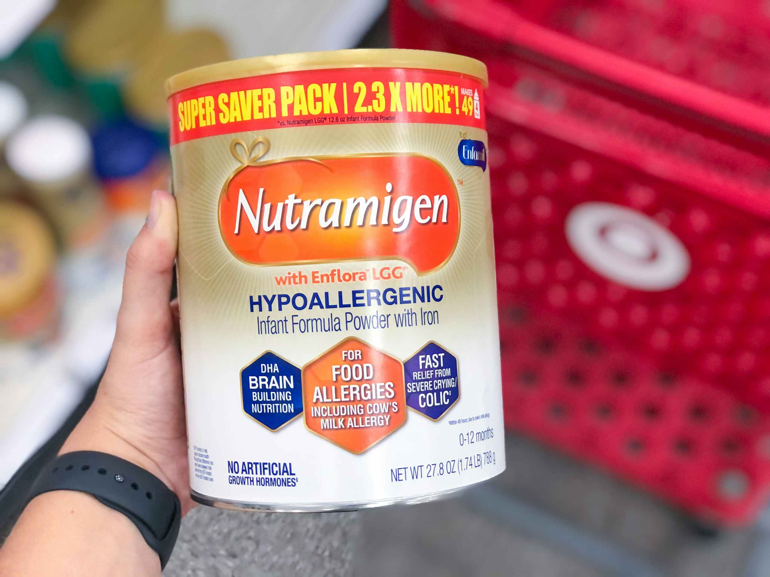 hand holding infant formula in in front of Target shopping cart