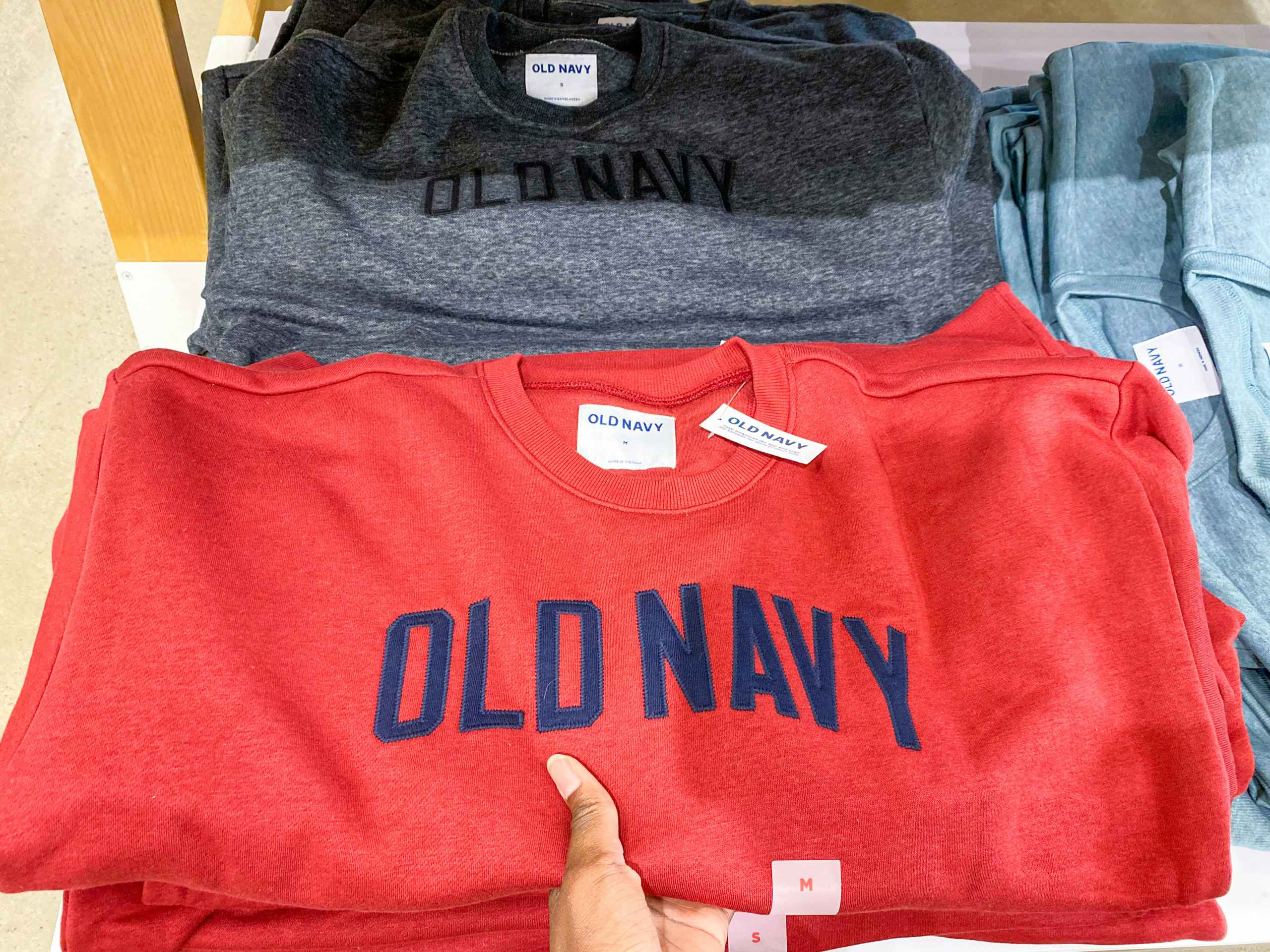 a mens old navy sweater held in hand on a table in old navy