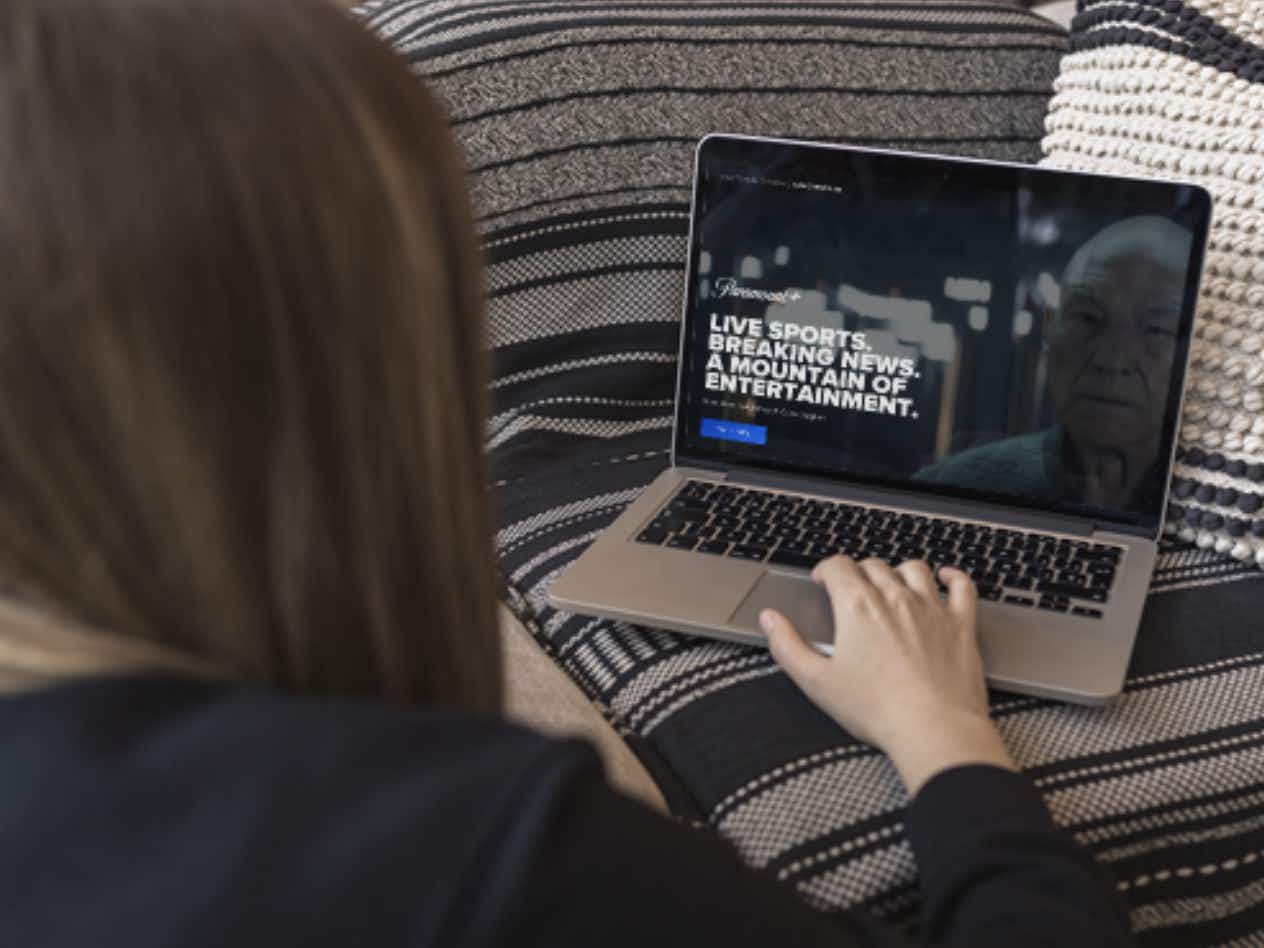 A person using a laptop displaying the Paramount Plus website.