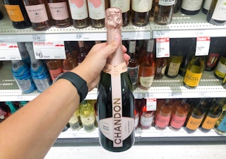 hand holding bottle of chandon sparkling rose wine in front of other wines
