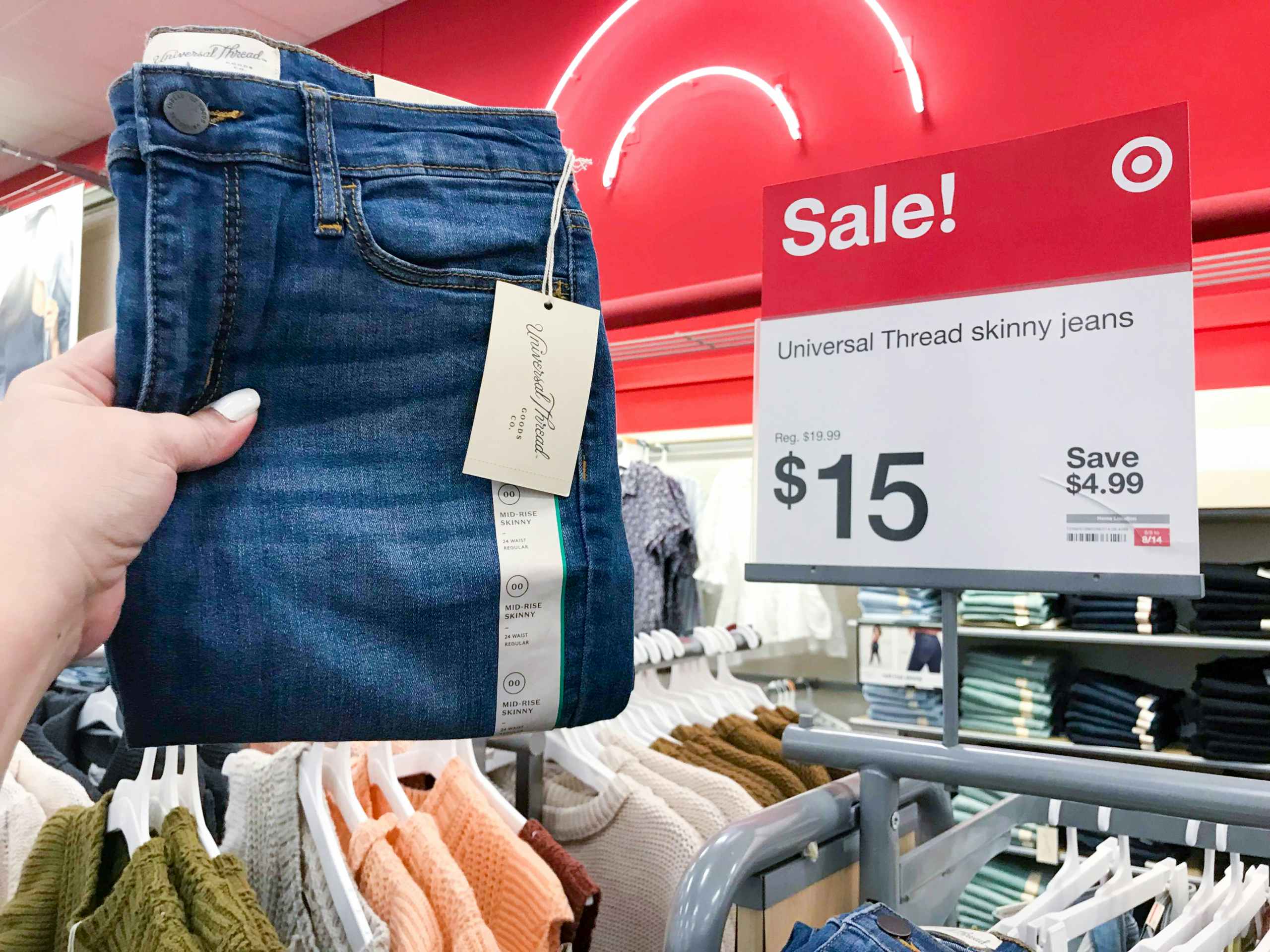 hand holding pair of jeans in front of $15 sale sign at Target