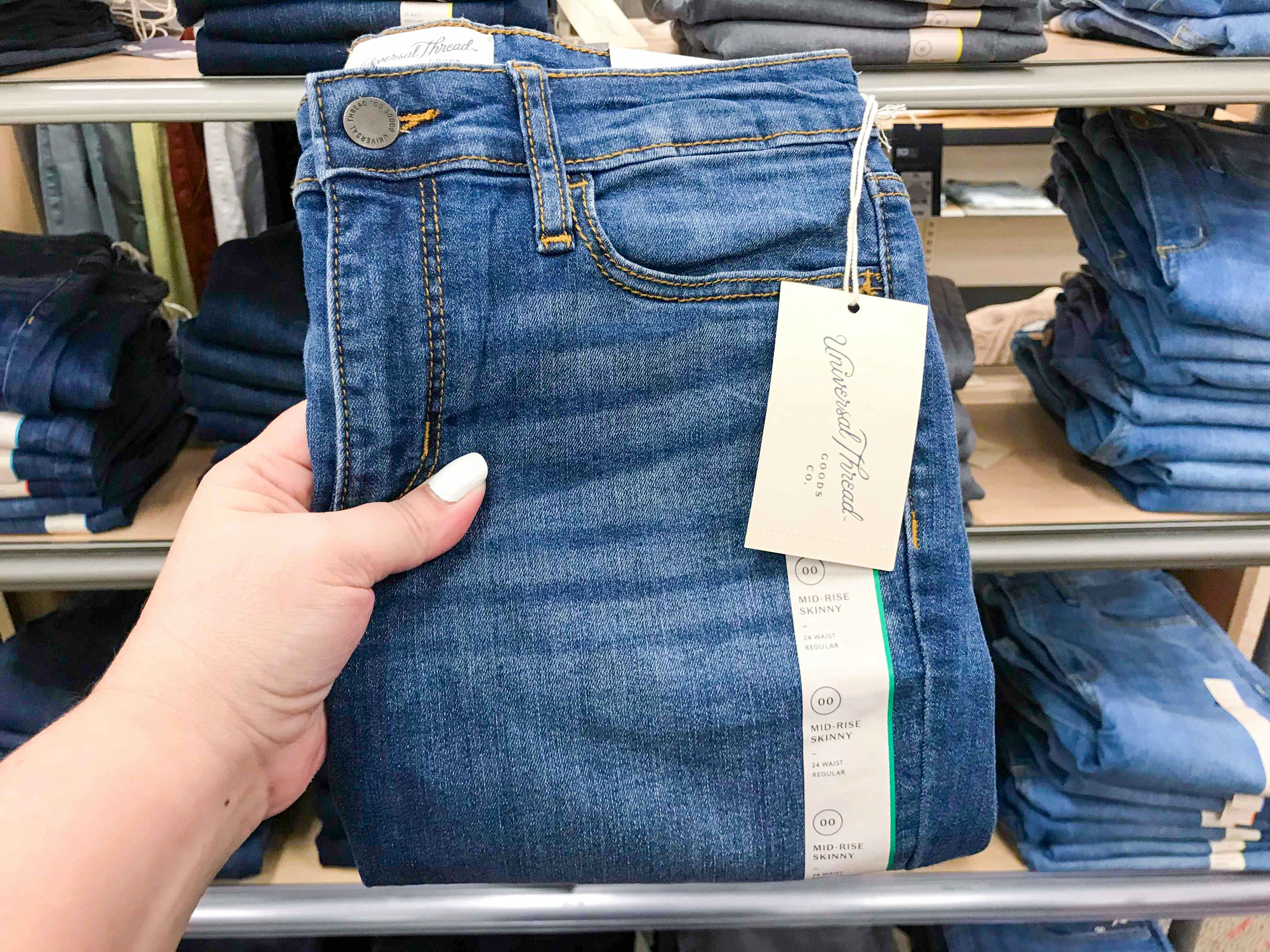hand holding pair of jeans in front of shelf at Target