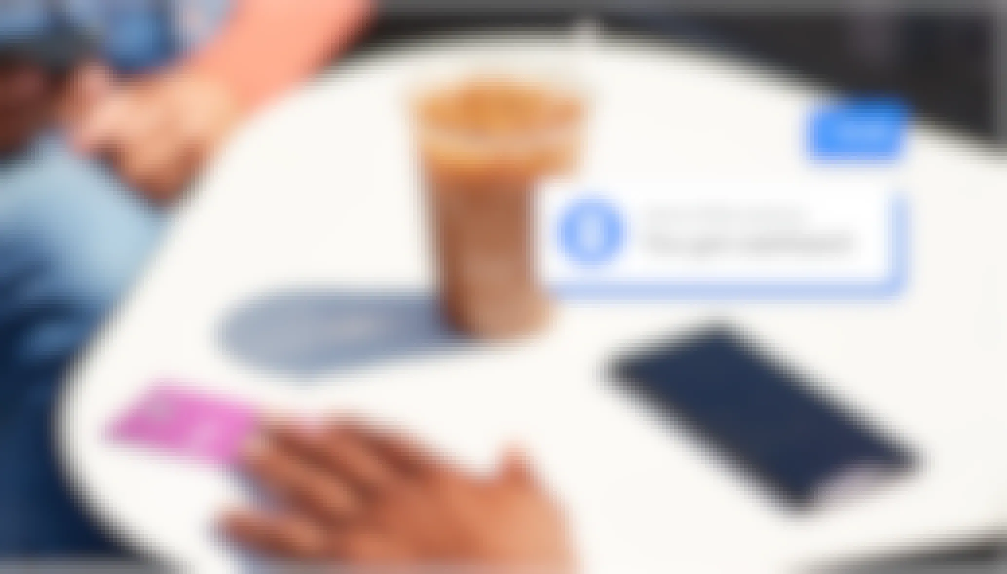 hand holding a venmo card on a table with coffee and cell phone