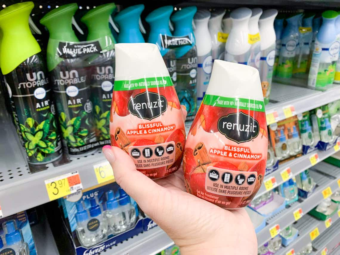 two renuzit adjustable air freshener cones in palm of hand in front of walmart shelves 