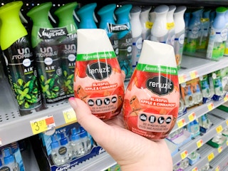 two renuzit adjustable air freshener cones in palm of hand in front of walmart shelves
