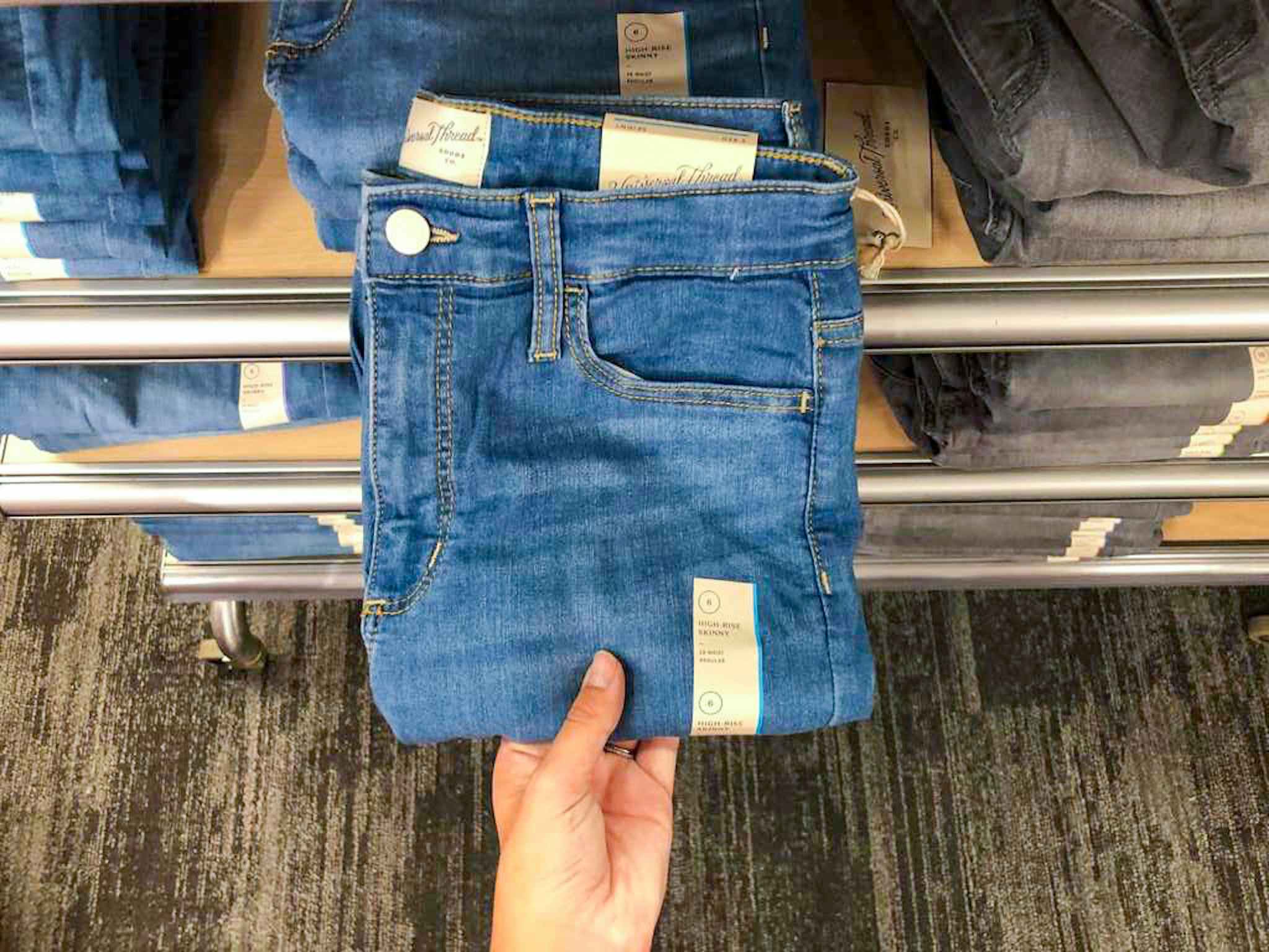 hand grabbing a pair of universal thread women's jeans off a target shelf