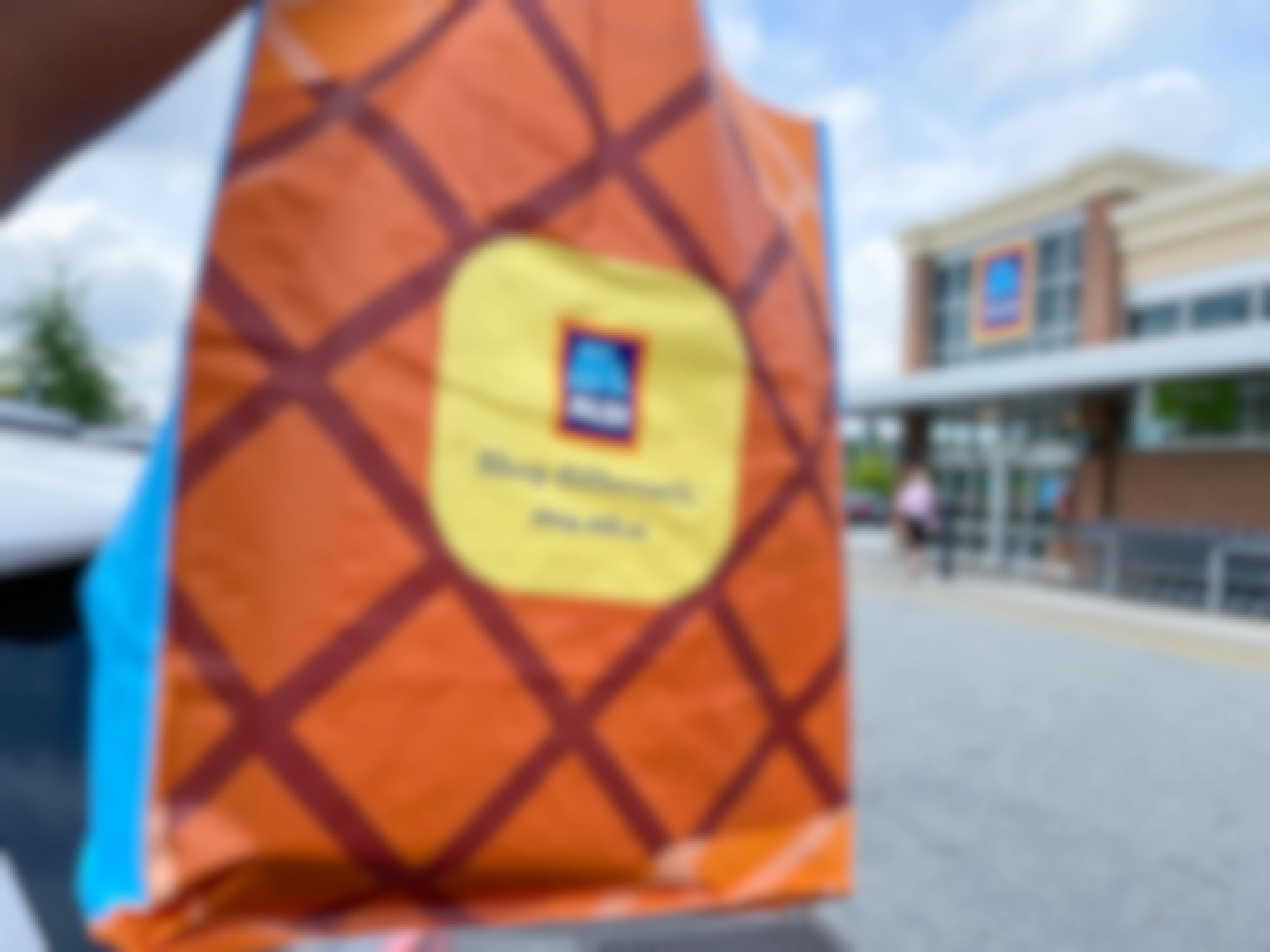 an Aldi reusable bag being held up in front of an Aldi store