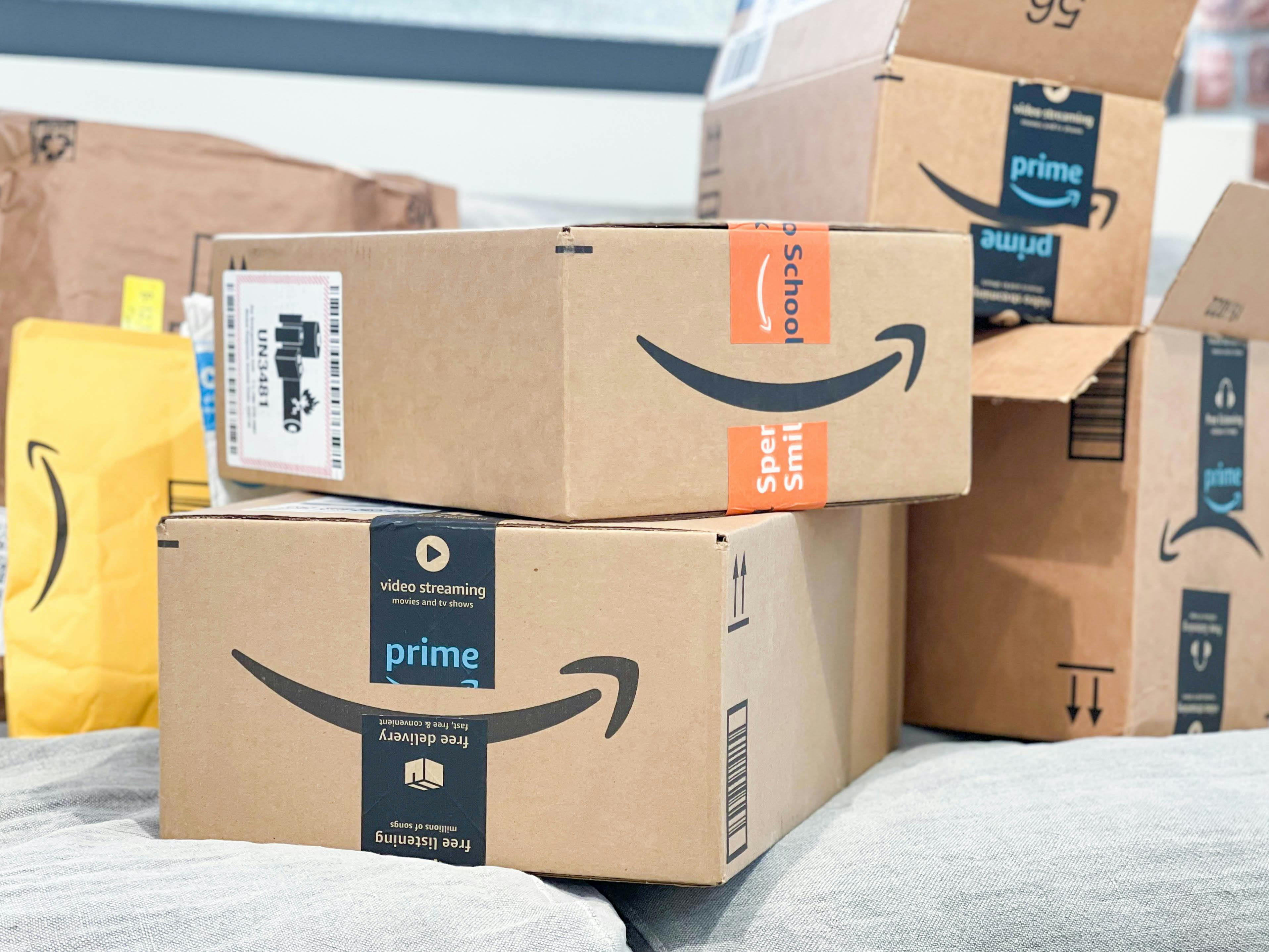 A bunch of Amazon packages and boxes stacked on a couch.
