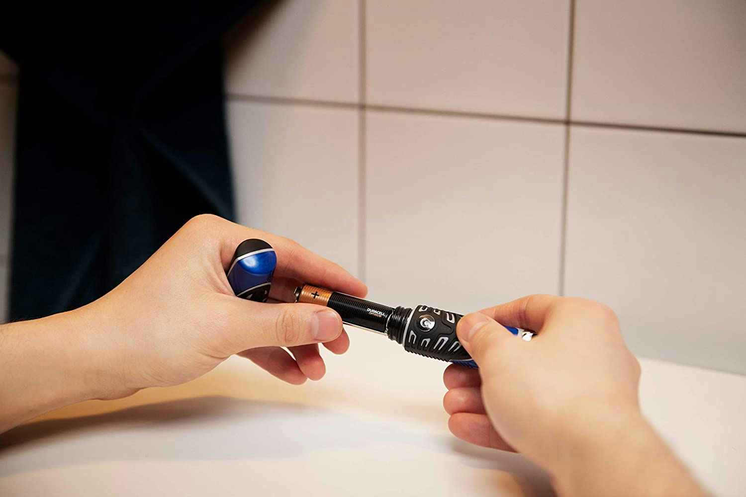 A person inserting a Durcell Optimum AAA battery into a device.