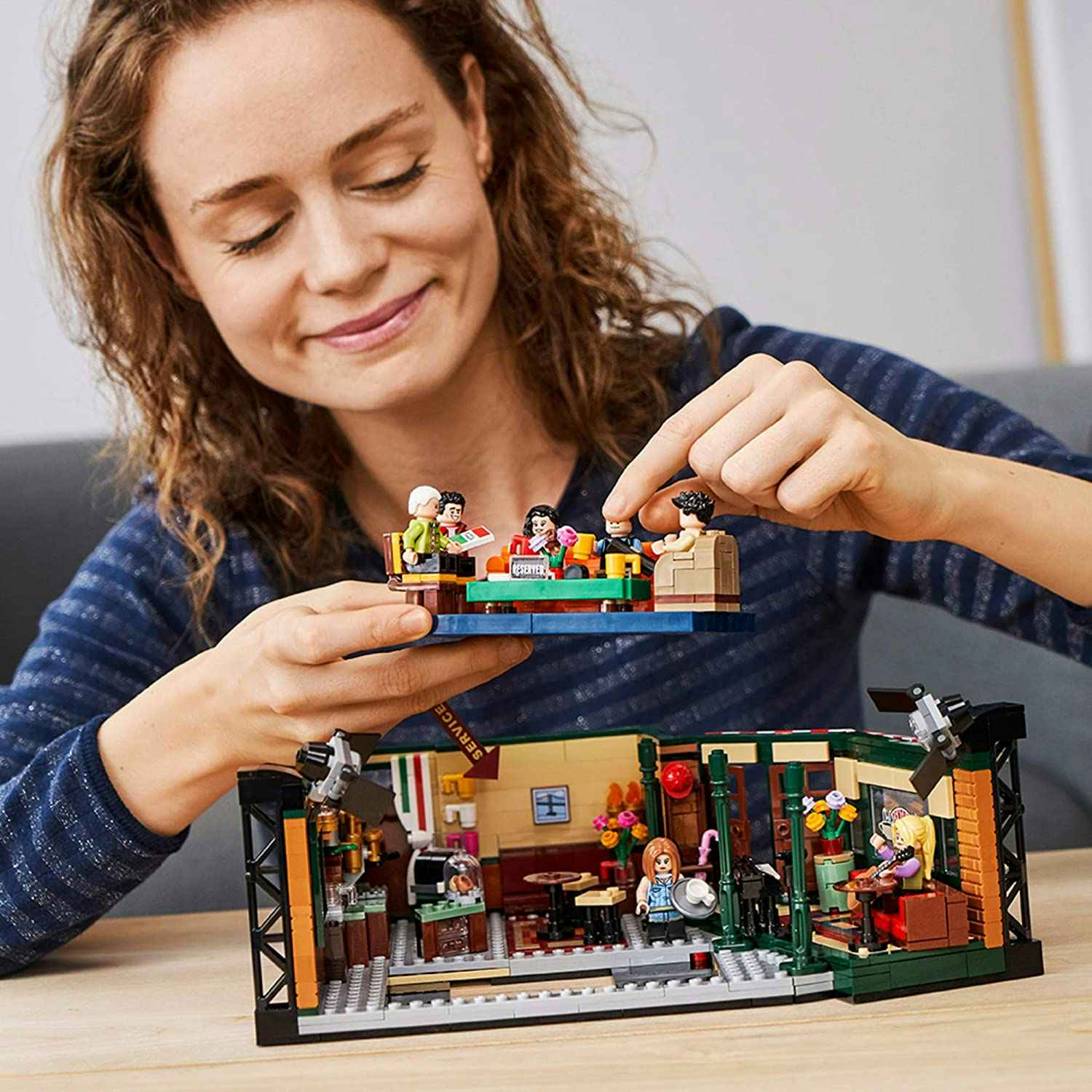A woman playing with a LEGO Friends building kit.