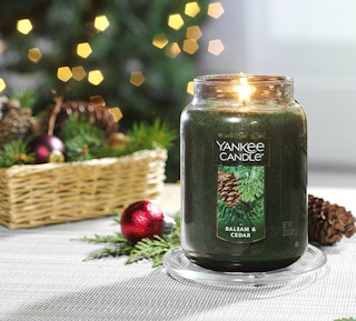 A Yankee Candle burning, with holiday decorations in the background.