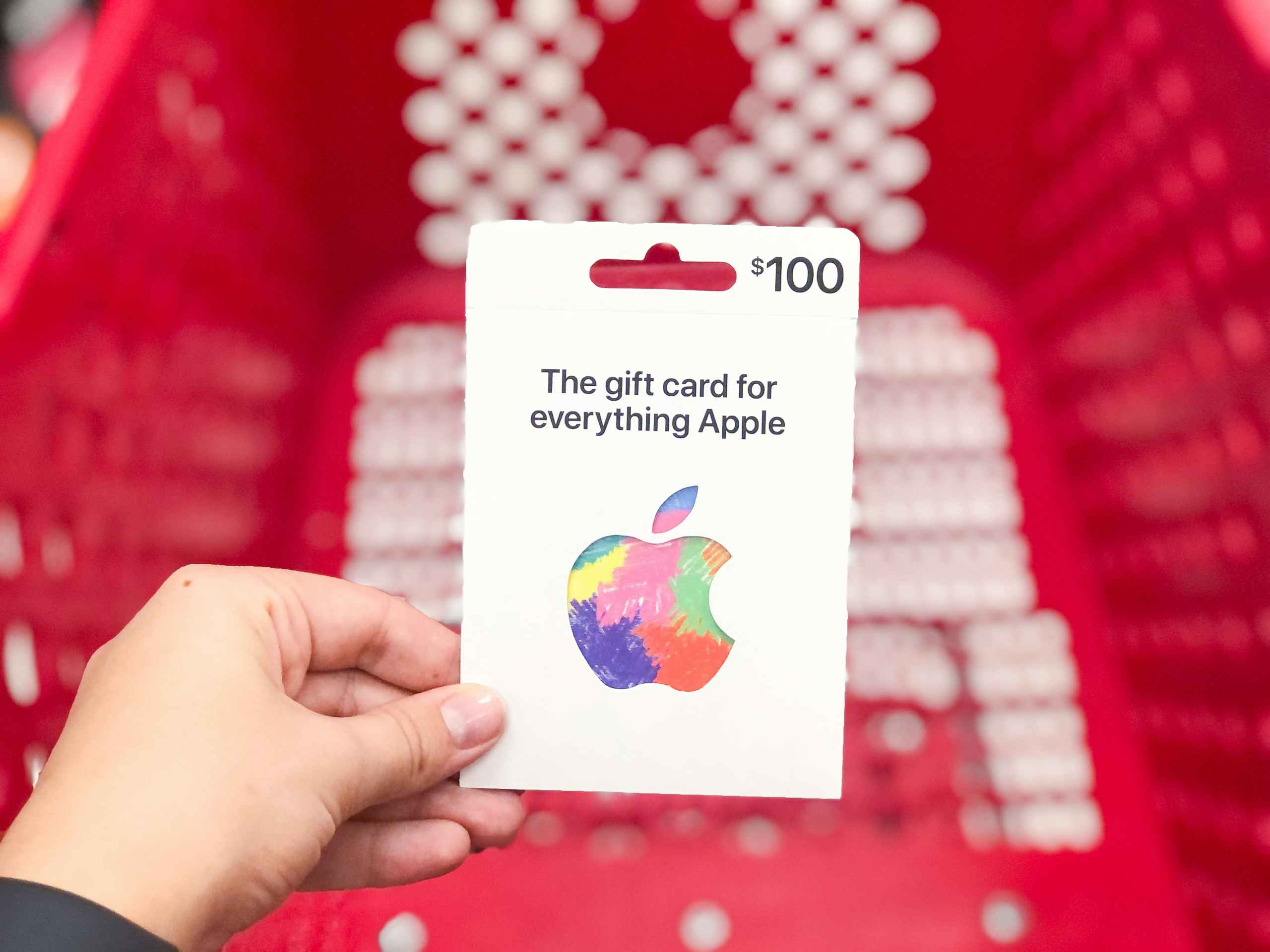 hand holding Apple gift card in front of shopping cart