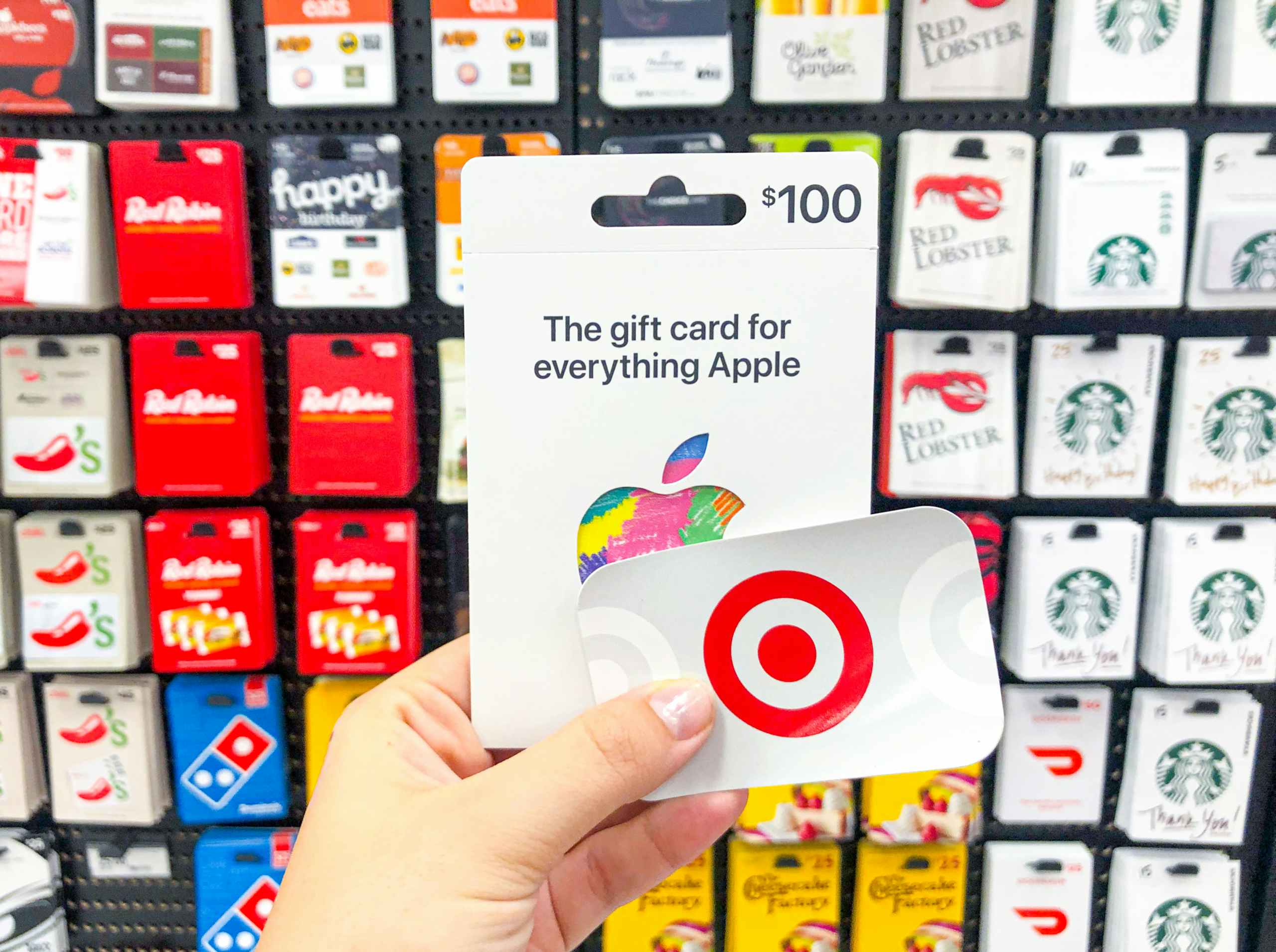hand holding Apple gift card and Target gift card in front of gift card display at Target
