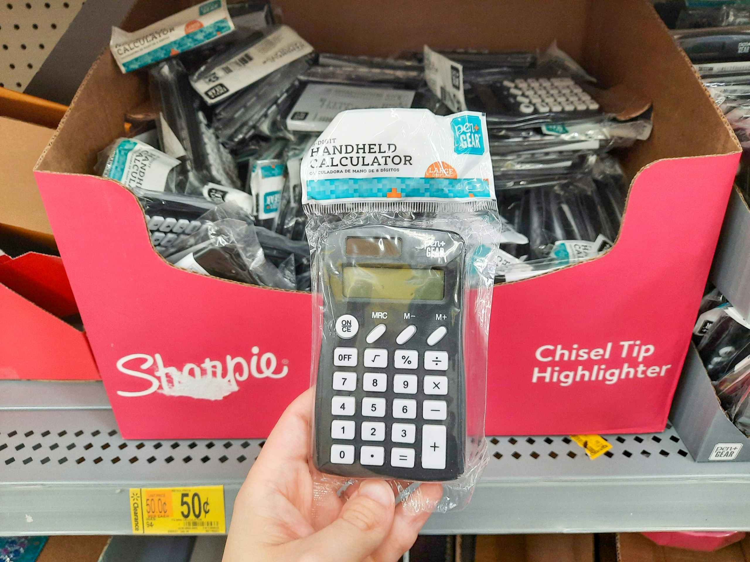 hand holding calculator at Walmart in front of store shelf
