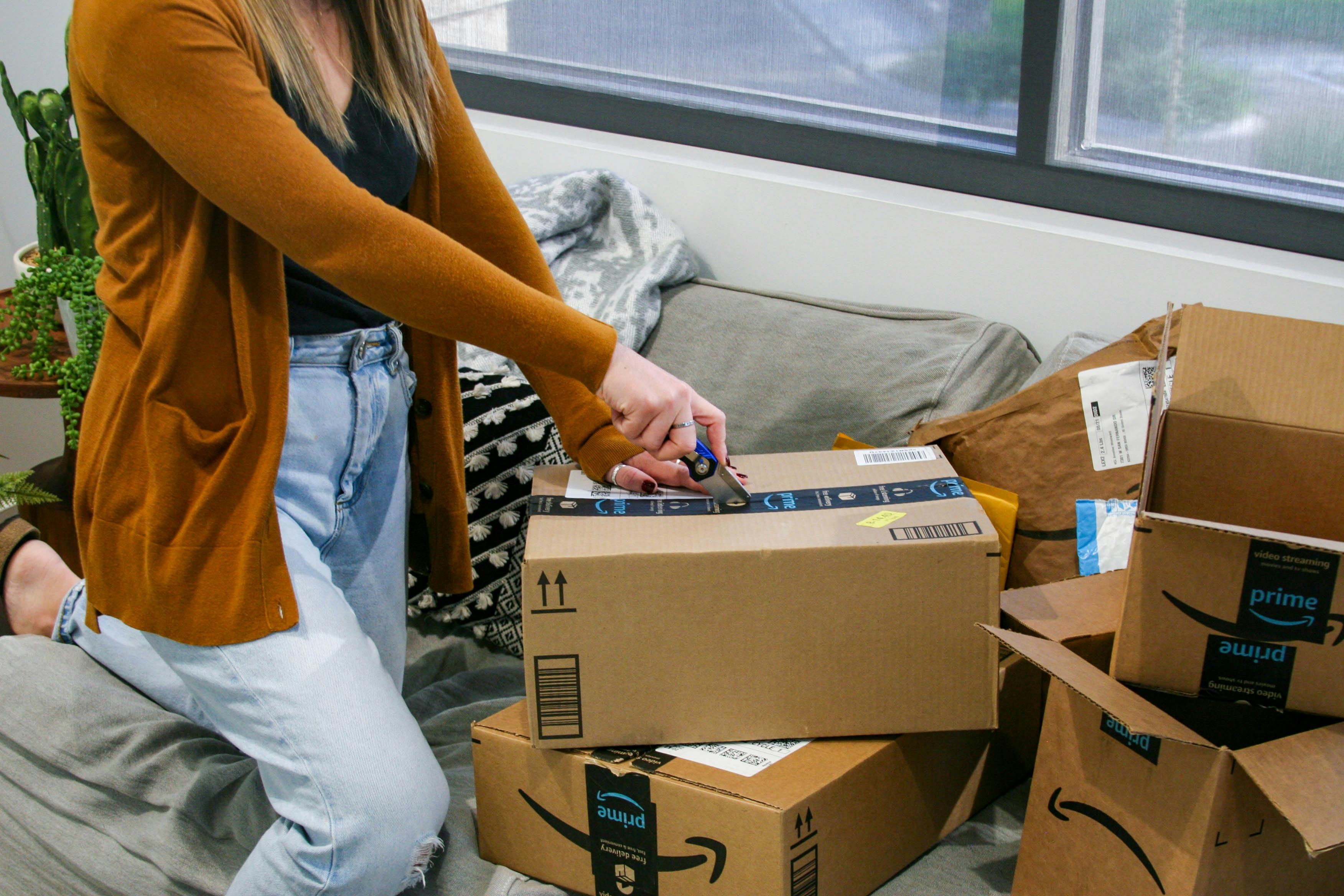 person using knife to open amazon box on couch