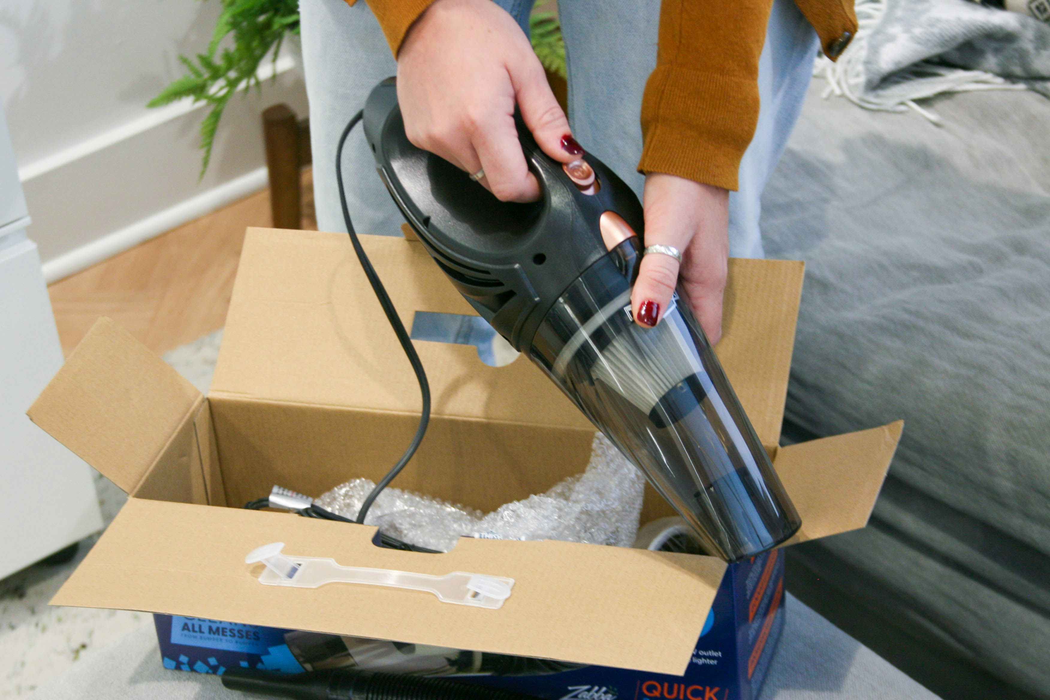 Corded car vacuum being held next to box