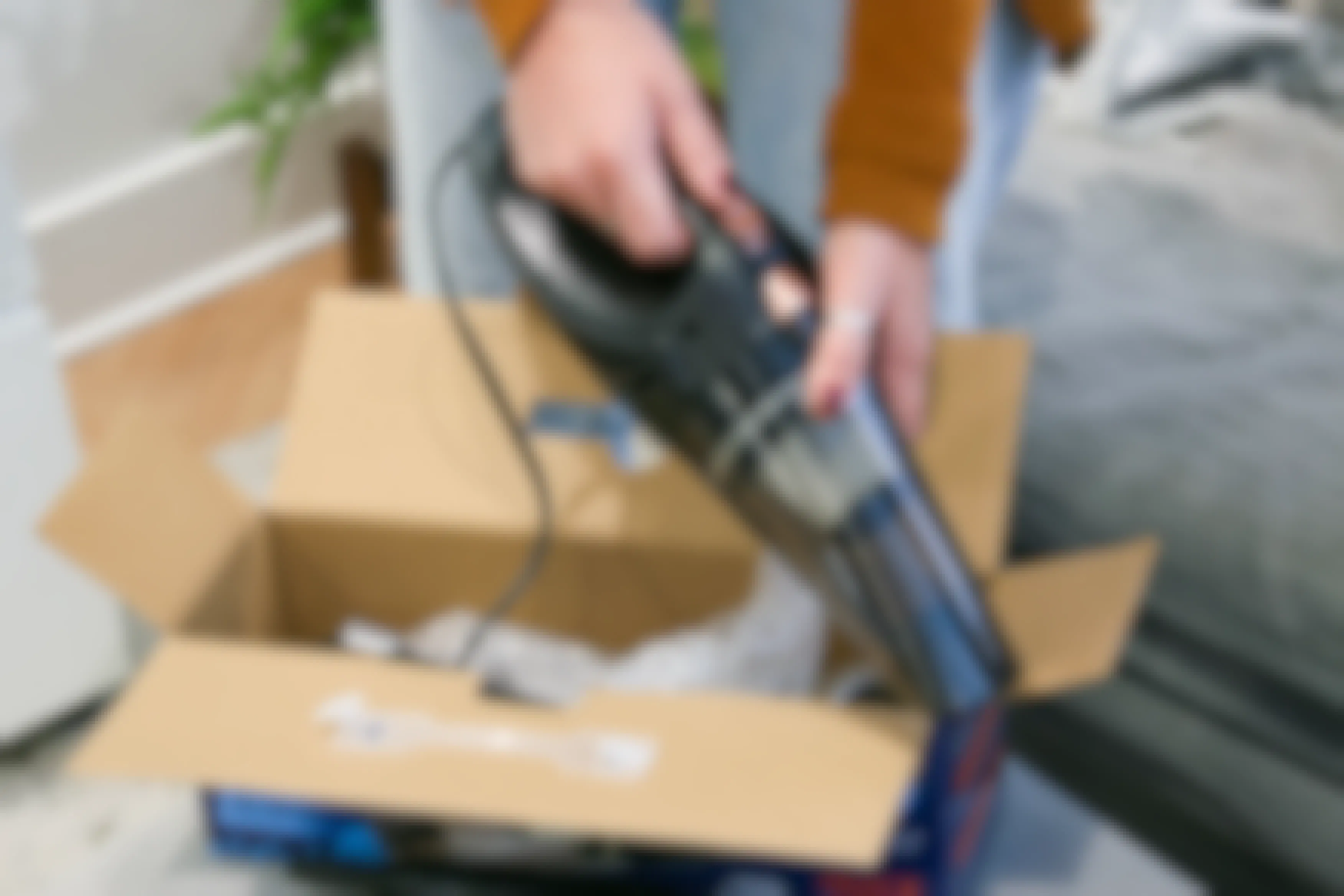 Corded car vacuum being held next to box