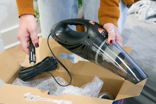 Corded car vacuum being held next to box