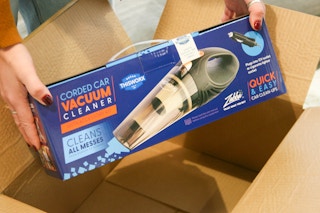 Corded car vacuum being held next to box