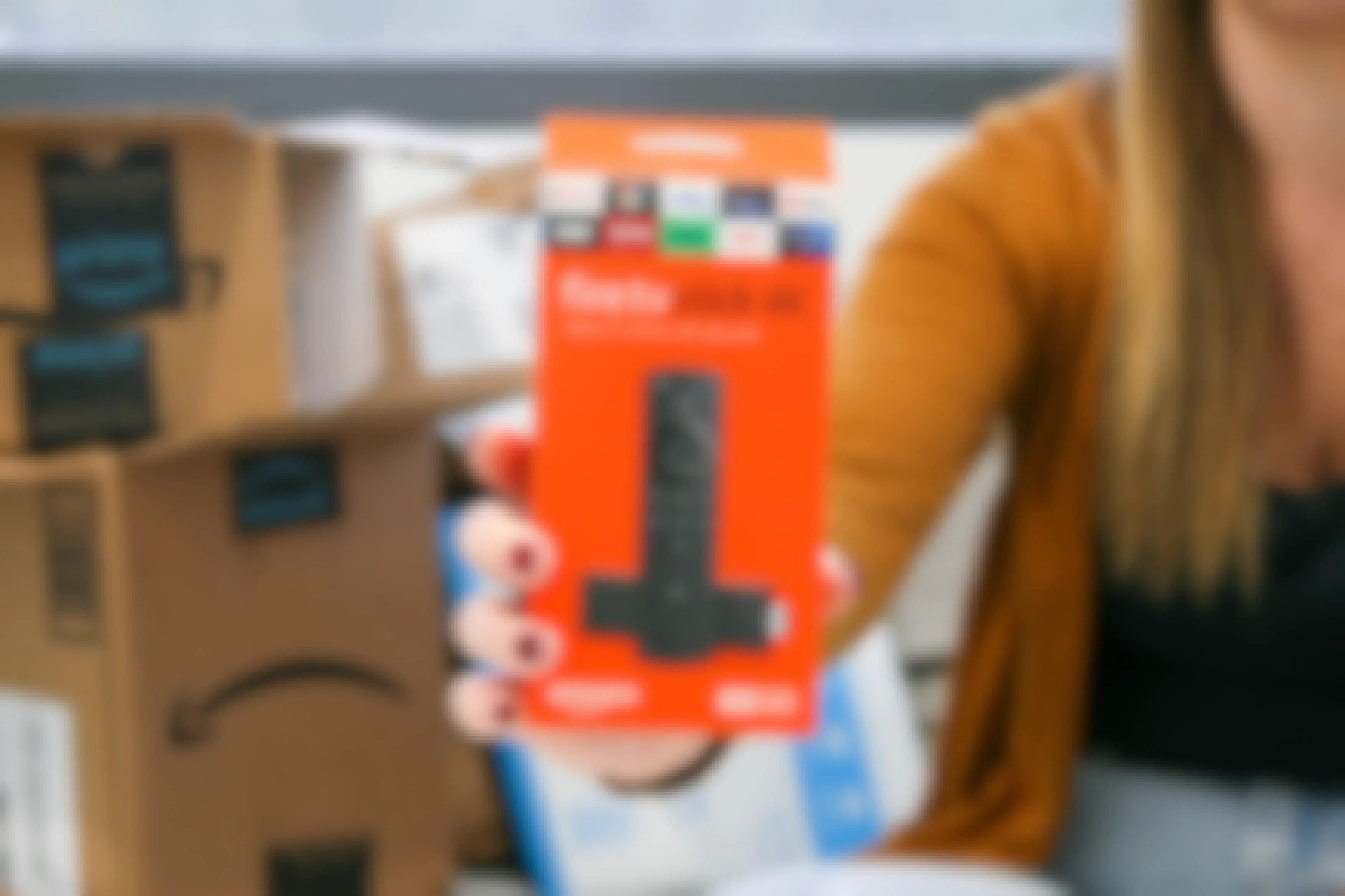 a person sitting down with a fire tv stick 4k being held with boxes in the background