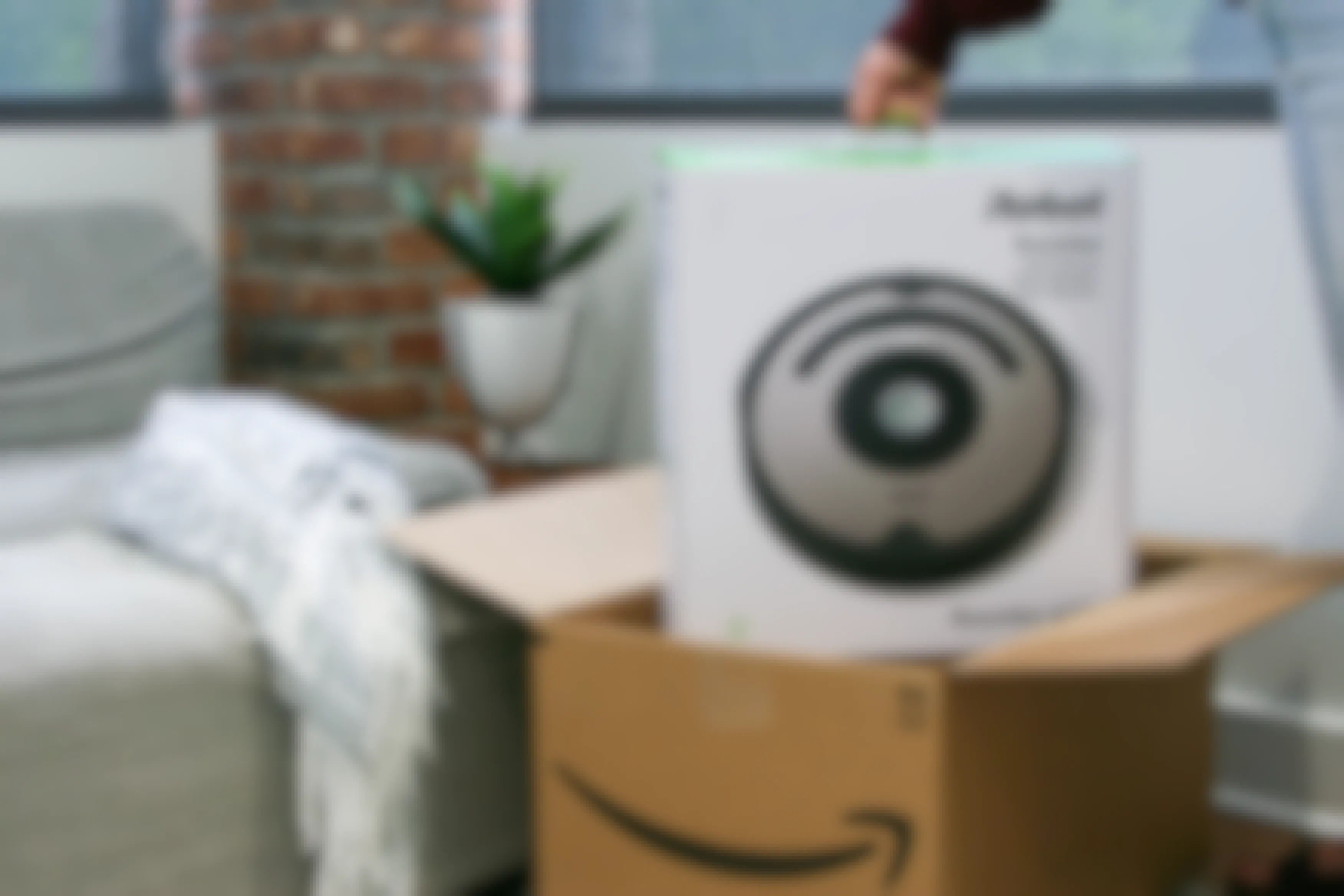 Someone taking an iRobot Roomba out of an Amazon box