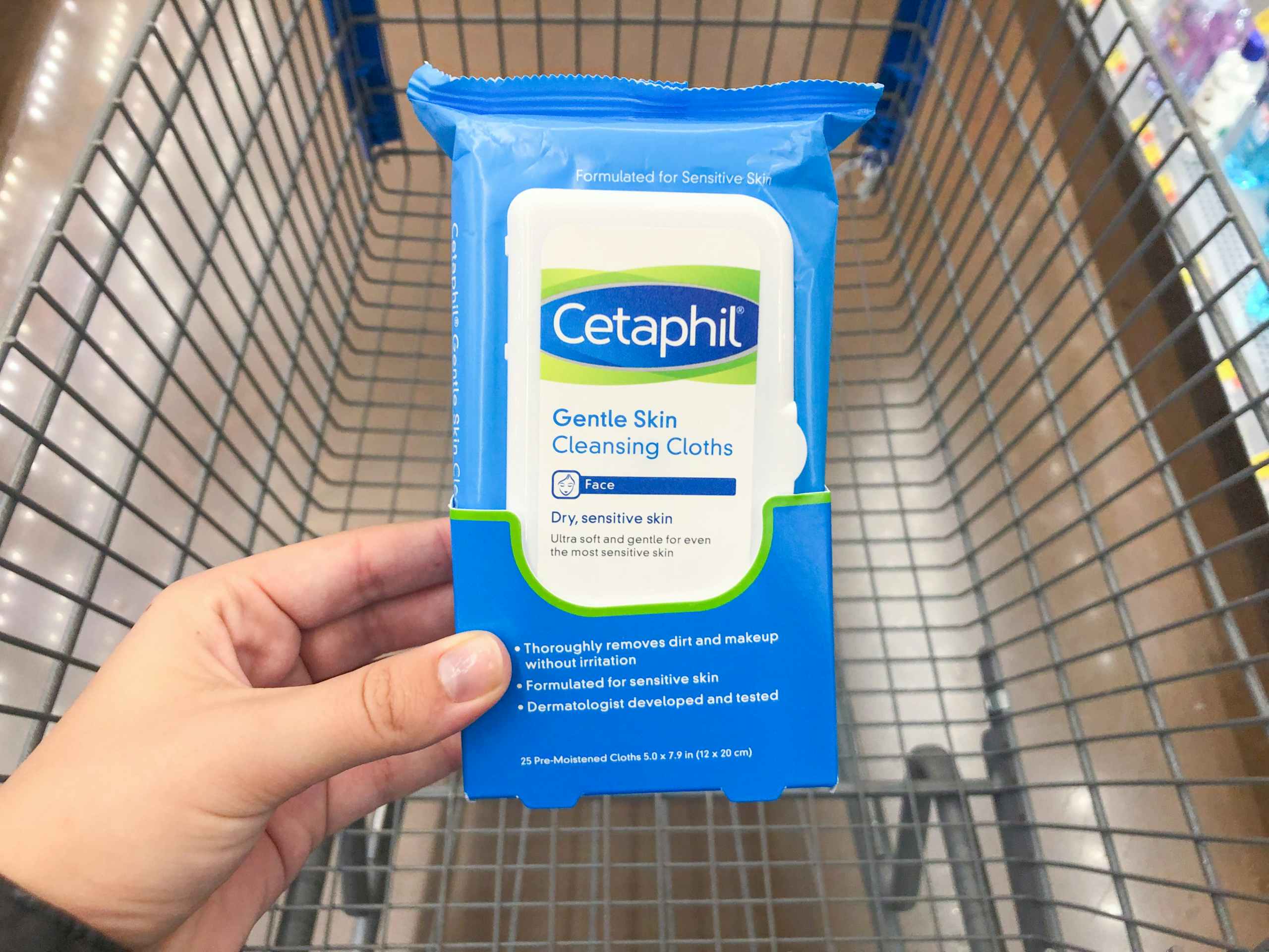 hand holding Cetaphil wipes over the top of Walmart shopping cart