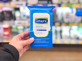 hand holding Cetaphil wipes in front of skin care aisle at Walmart