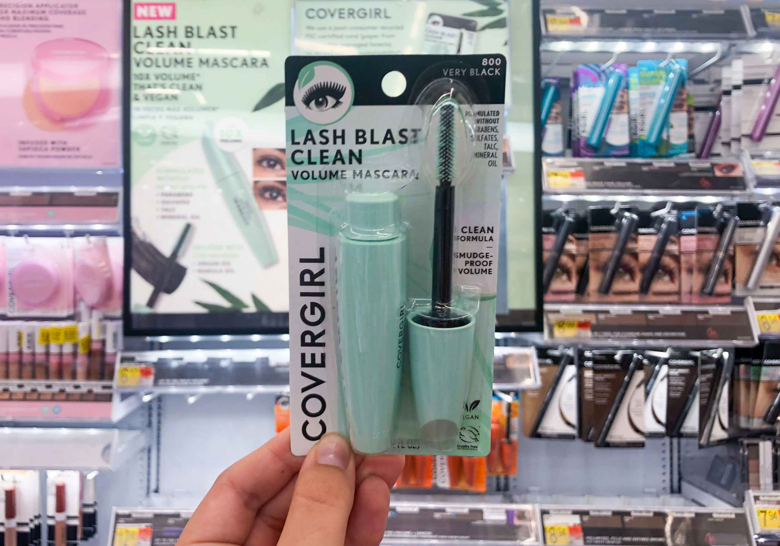 hand holding mascara in front of store Covergirl display