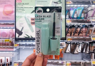 hand holding mascara in front of store Covergirl display
